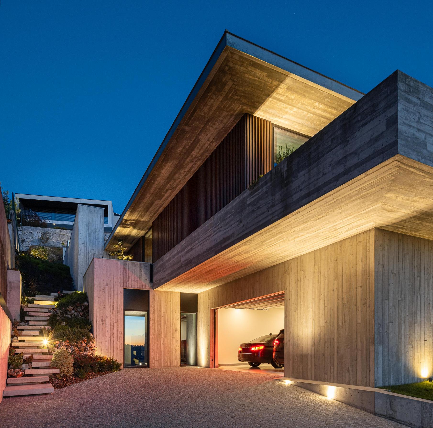 Exterior: Alpendre com piscina iluminada e vista para a paisagem ao anoitecer. — CASA A arquitetura L2C Arquitetura em Braga