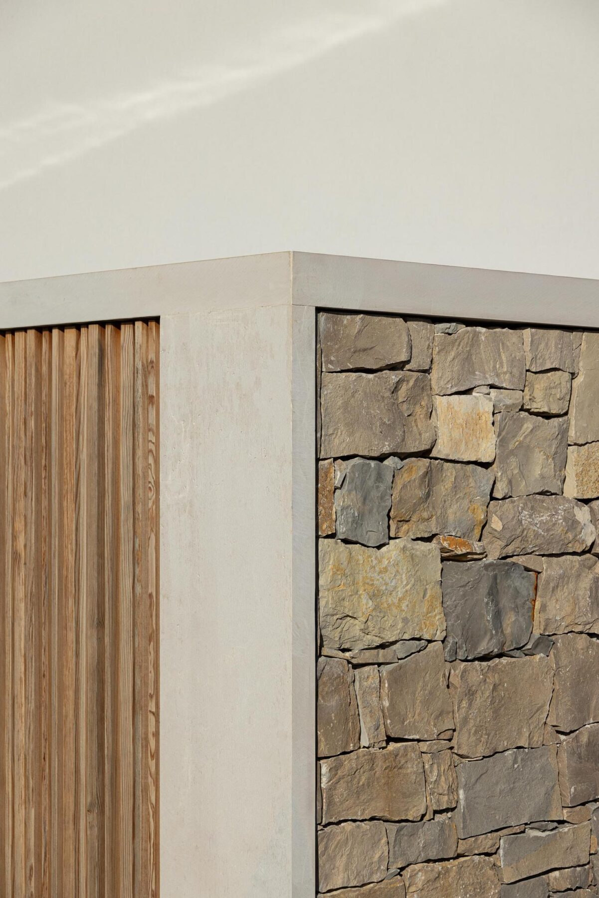 Detalhe arquitetónico: Canto da casa com madeira vertical, pedra rústica e reboco branco. — WEST CLIFFS D45 arquitetura ARX Portugal - Arquitectos em Óbidos