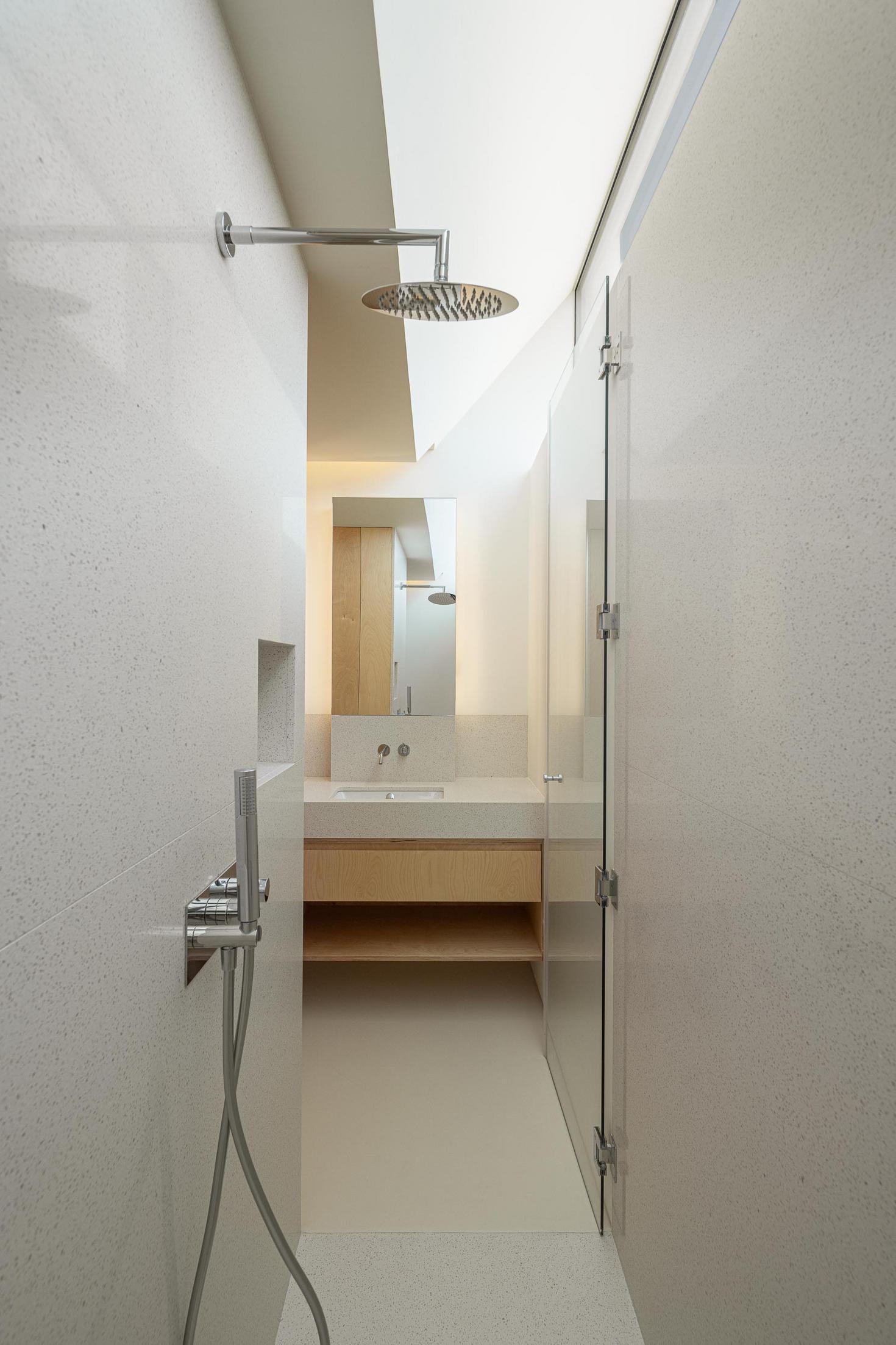 Casa de banho: Cabine de duche com revestimento branco, lavatório e espelho ao fundo. — WEST CLIFFS D45 arquitetura ARX Portugal - Arquitectos em Óbidos