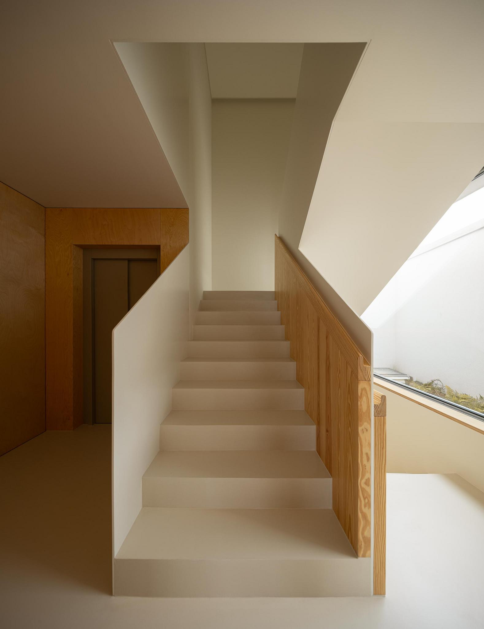 Escadaria: Escada com corrimão em madeira, elevador e janela para o pátio interior. — WEST CLIFFS D45 arquitetura ARX Portugal - Arquitectos em Óbidos