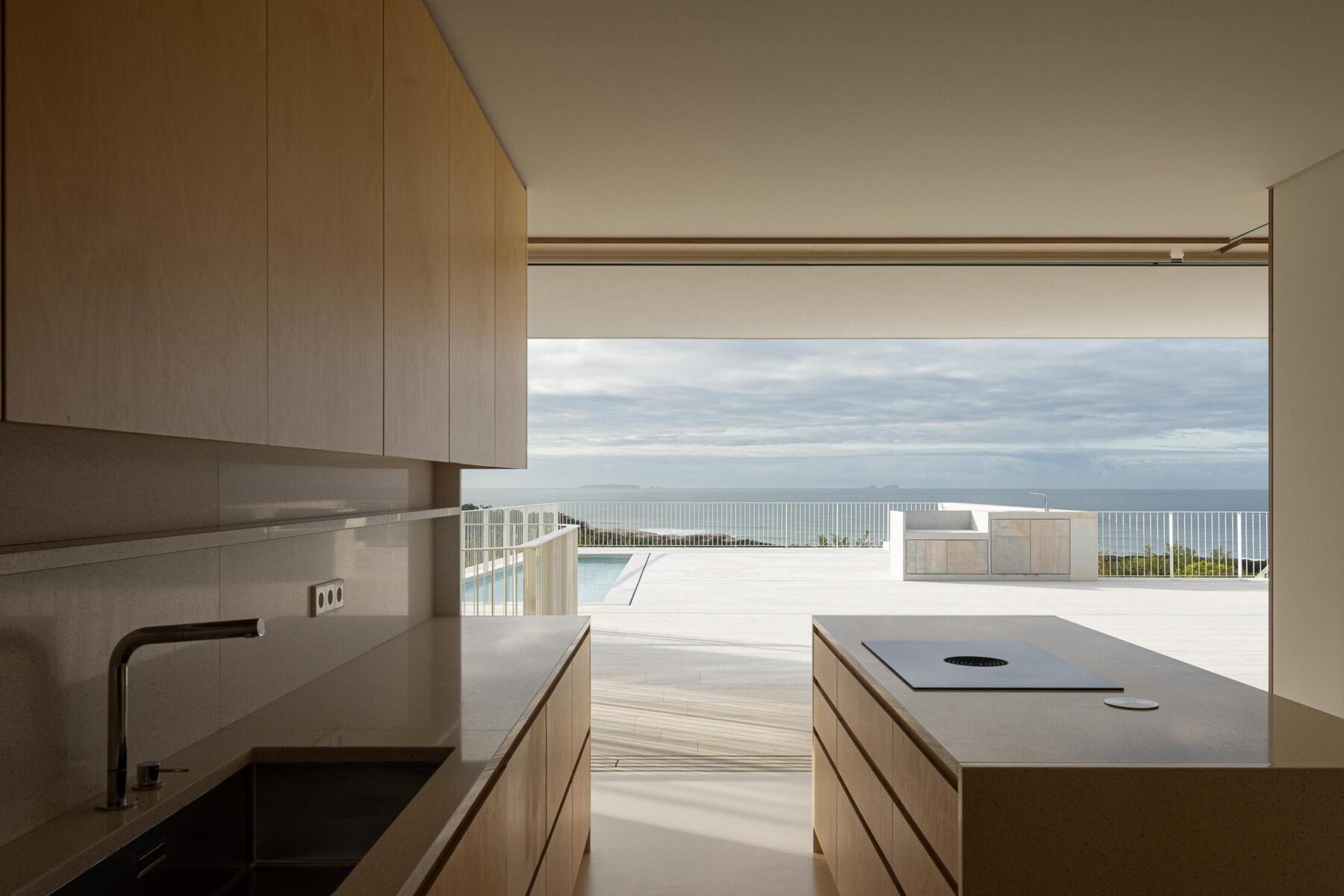 Cozinha: Vista da cozinha para o terraço exterior com piscina e vista para o mar. — WEST CLIFFS D45 arquitetura ARX Portugal - Arquitectos em Óbidos