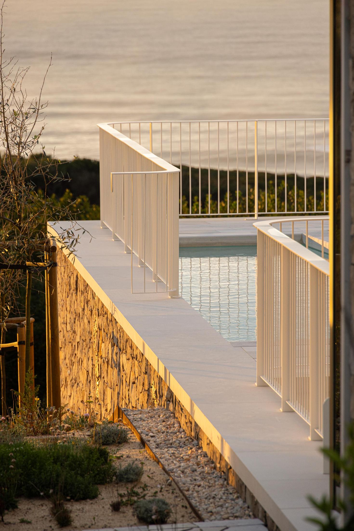 Jardim: Detalhe da piscina com vedação branca e jardim com vegetação rasteira. — WEST CLIFFS D45 arquitetura ARX Portugal - Arquitectos em Óbidos
