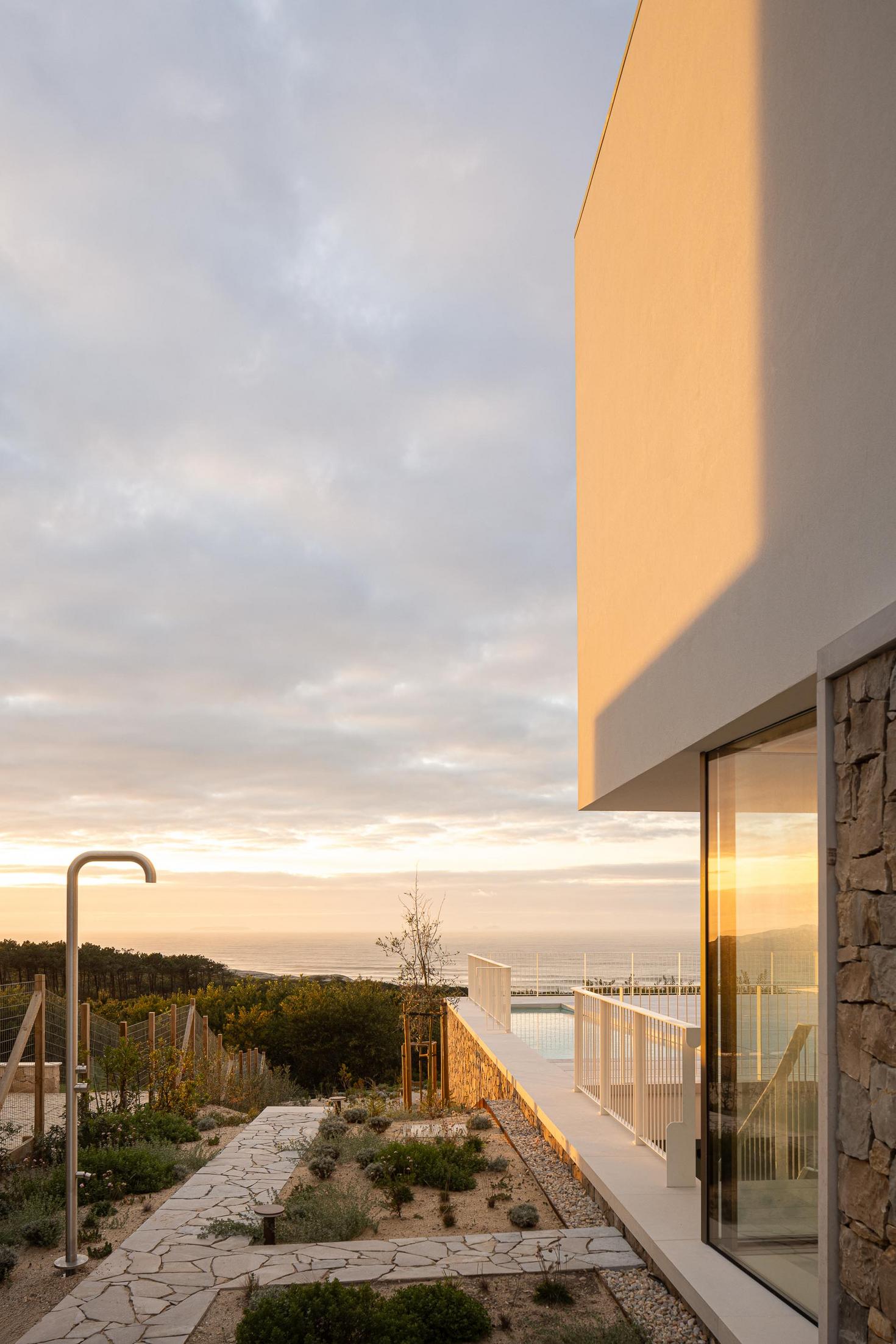 Jardim: Vista da casa com jardim, caminho em pedra e piscina ao fundo. — WEST CLIFFS D45 arquitetura ARX Portugal - Arquitectos em Óbidos