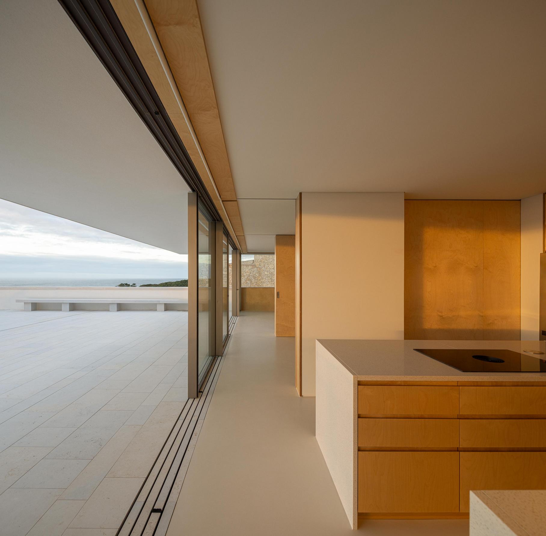 Cozinha: Cozinha com ilha central, grandes janelas e vista para o terraço. — WEST CLIFFS D45 arquitetura ARX Portugal - Arquitectos em Óbidos