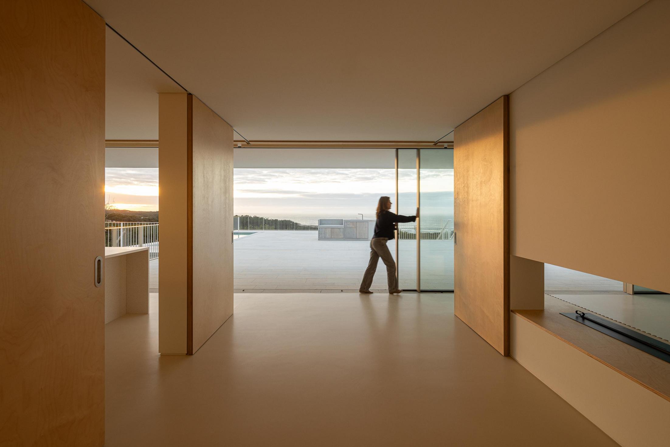 Sala: Sala de estar com divisórias em madeira e vista para o terraço com piscina. — WEST CLIFFS D45 arquitetura ARX Portugal - Arquitectos em Óbidos