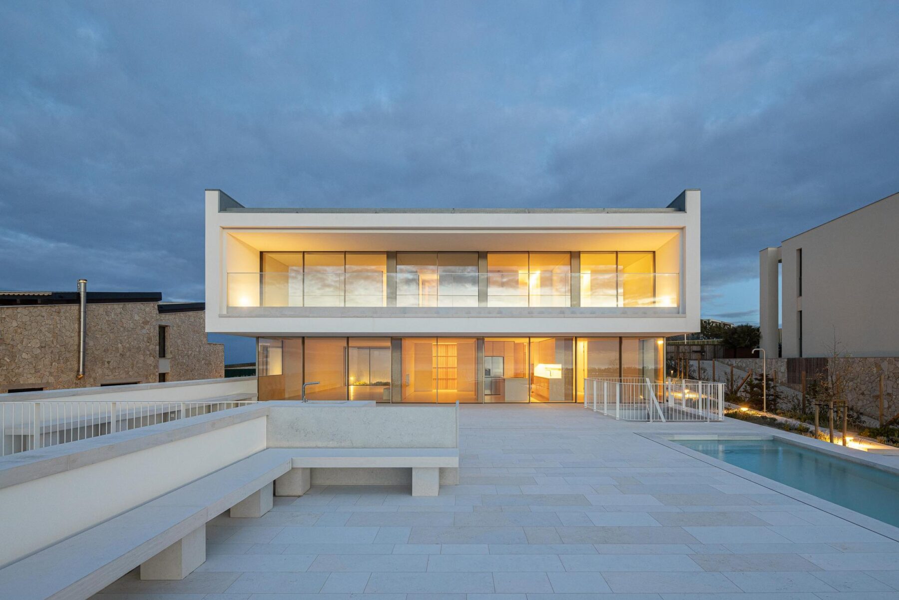 Fachada posterior: Vista noturna da fachada posterior com terraço, piscina e iluminação. — WEST CLIFFS D45 arquitetura ARX Portugal - Arquitectos em Óbidos