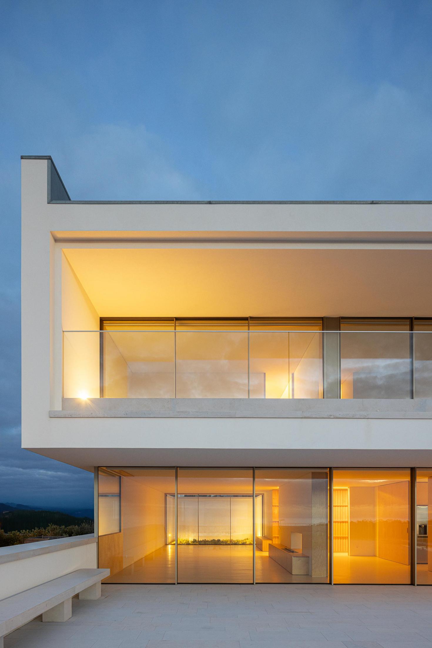 Fachada lateral: Detalhe noturno da fachada com varanda envidraçada e iluminação. — WEST CLIFFS D45 arquitetura ARX Portugal - Arquitectos em Óbidos