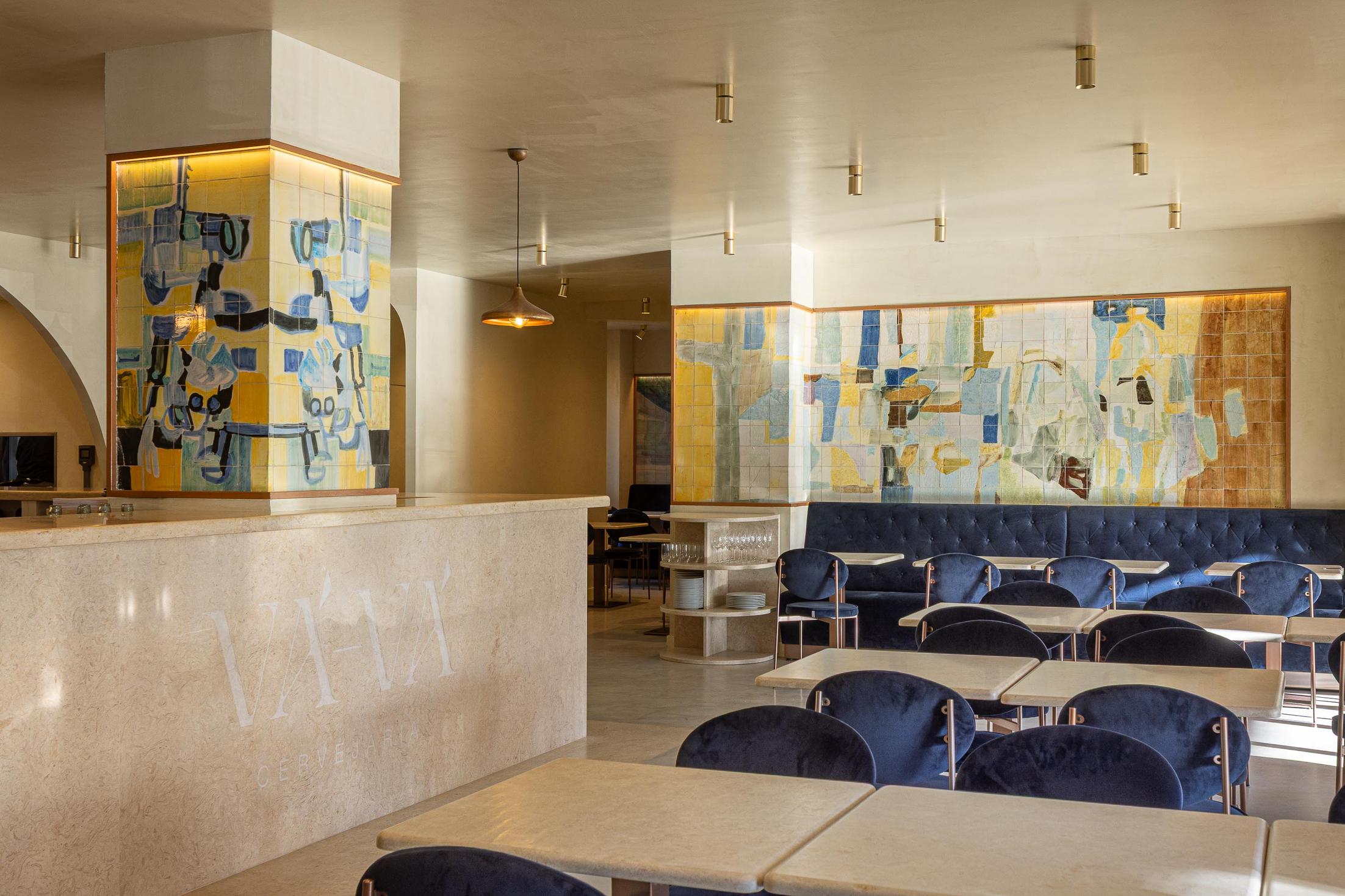 Salão: Vista geral com balcão em pedra, painel de azulejos coloridos, mesas de mármore e cadeiras de veludo azul. — Cervejaria Vává - Requalificação arquitetura Rethorica Studio em Lisboa