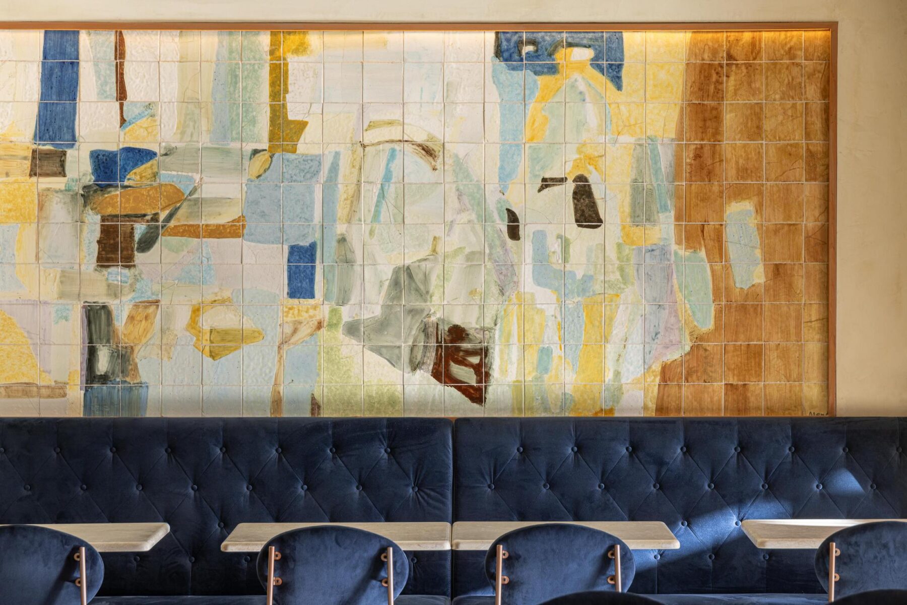 Salão: Detalhe do painel de azulejos com motivos abstractos sobre um sofá corrido de veludo azul. — Cervejaria Vává - Requalificação arquitetura Rethorica Studio em Lisboa