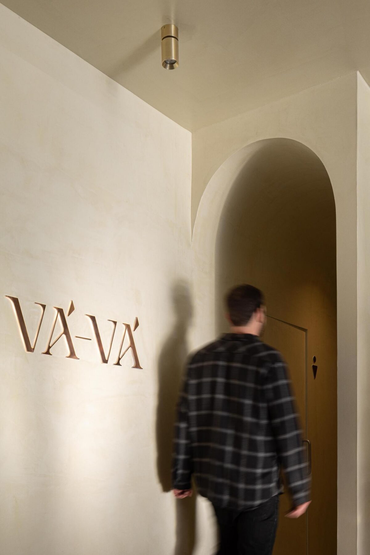 Entrada: Sinalética "Vá-Vá" em metal, arco e porta para a casa de banho com símbolo masculino. — Cervejaria Vává - Requalificação arquitetura Rethorica Studio em Lisboa