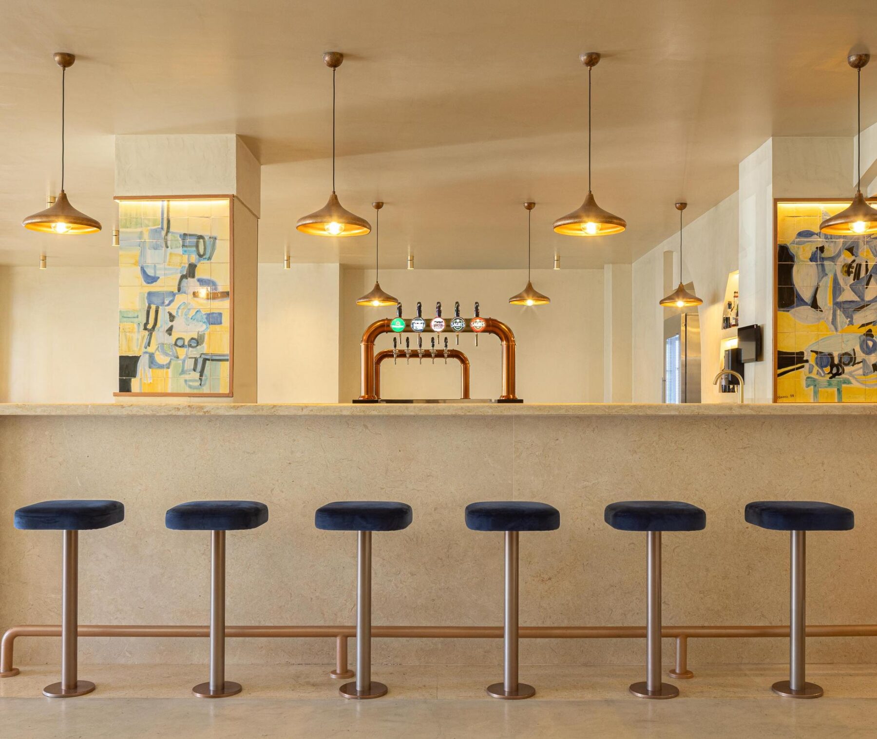 Salão: Balcão com bancos altos de veludo azul e painéis de azulejos coloridos. — Cervejaria Vává - Requalificação arquitetura Rethorica Studio em Lisboa