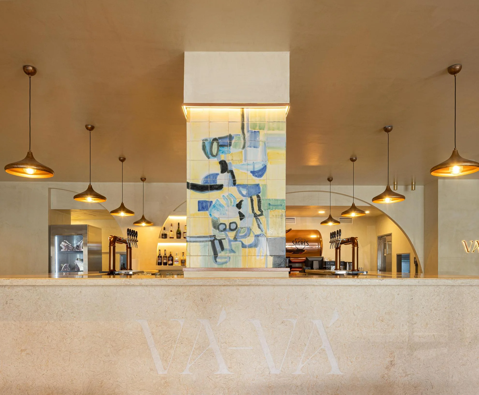 Balc&atilde;o: Vista frontal do balc&atilde;o com painel de azulejos, candeeiros suspensos e garrafeira. &mdash; Cervejaria V&aacute;v&aacute; - Requalifica&ccedil;&atilde;o arquitetura Rethorica Studio em Lisboa