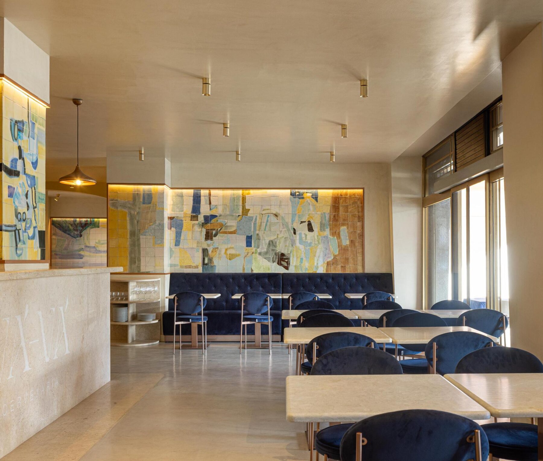 Salão: Vista geral do salão com balcão, painel de azulejos, mesas e cadeiras de veludo azul. — Cervejaria Vává - Requalificação arquitetura Rethorica Studio em Lisboa