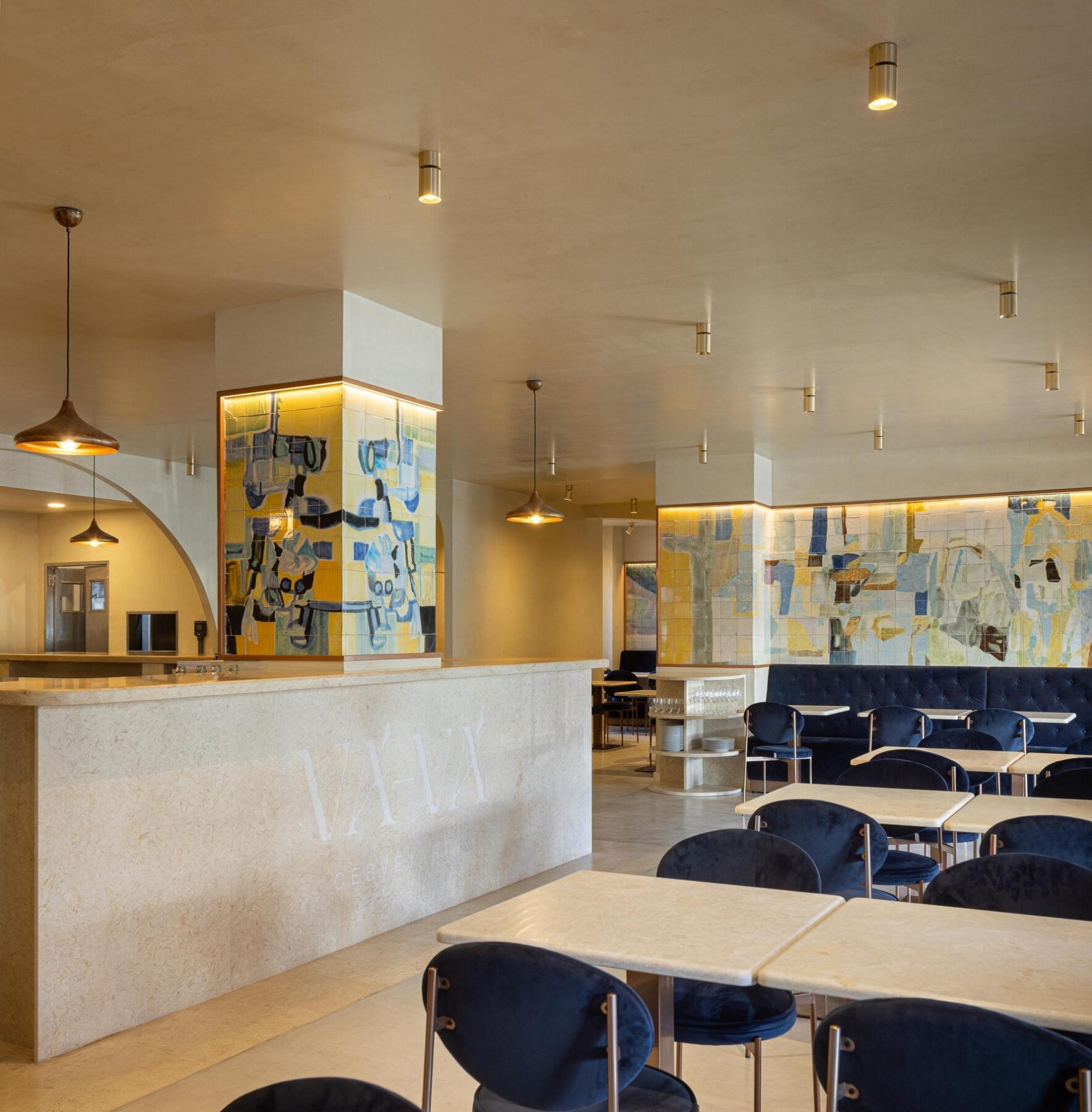 Salão: Vista geral do salão com balcão, painel de azulejos, mesas e cadeiras de veludo azul. — Cervejaria Vává - Requalificação arquitetura Rethorica Studio em Lisboa