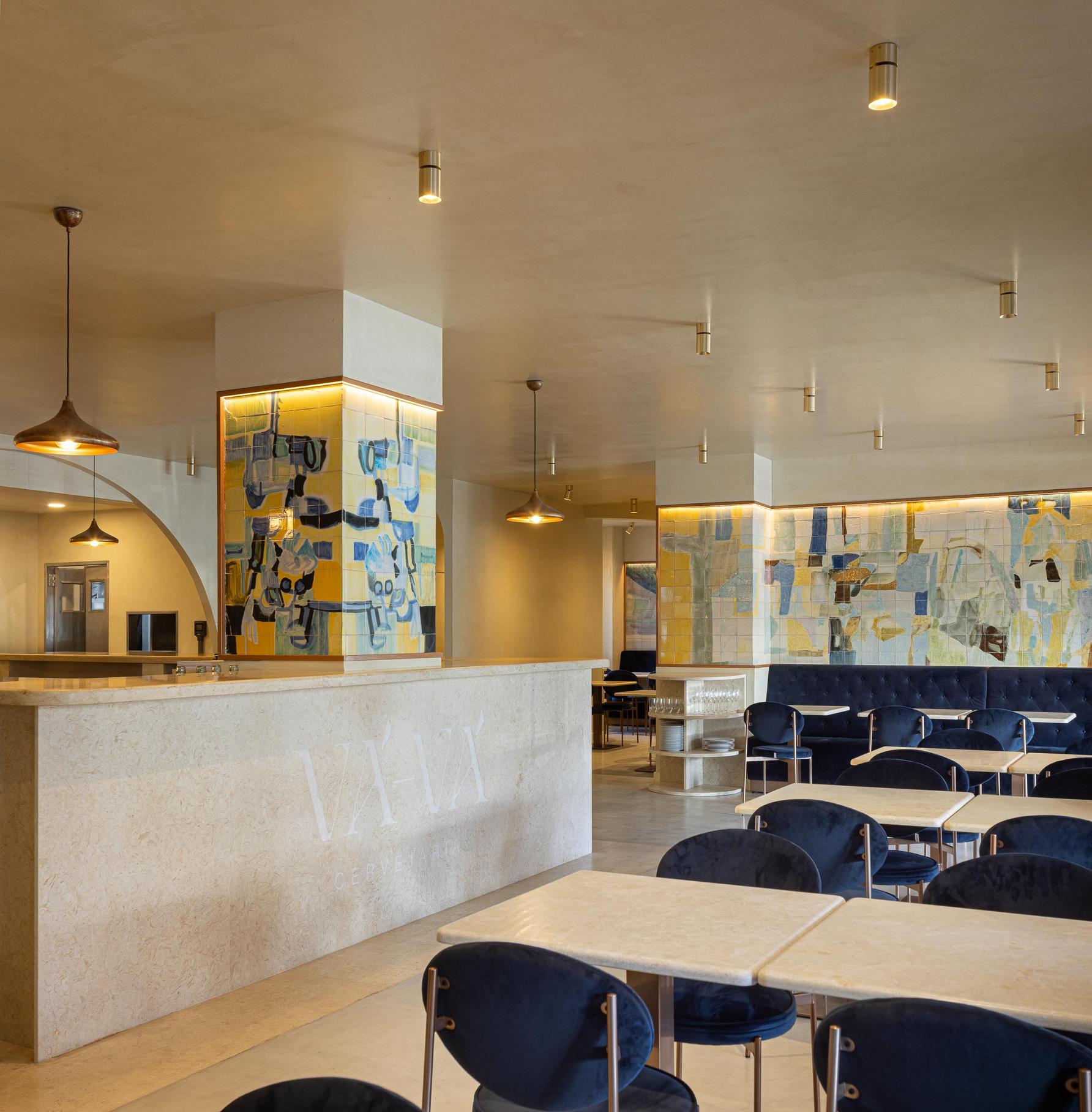 Salão: Vista geral do salão com balcão, painel de azulejos, mesas e cadeiras de veludo azul. — Cervejaria Vává - Requalificação arquitetura Rethorica Studio em Lisboa