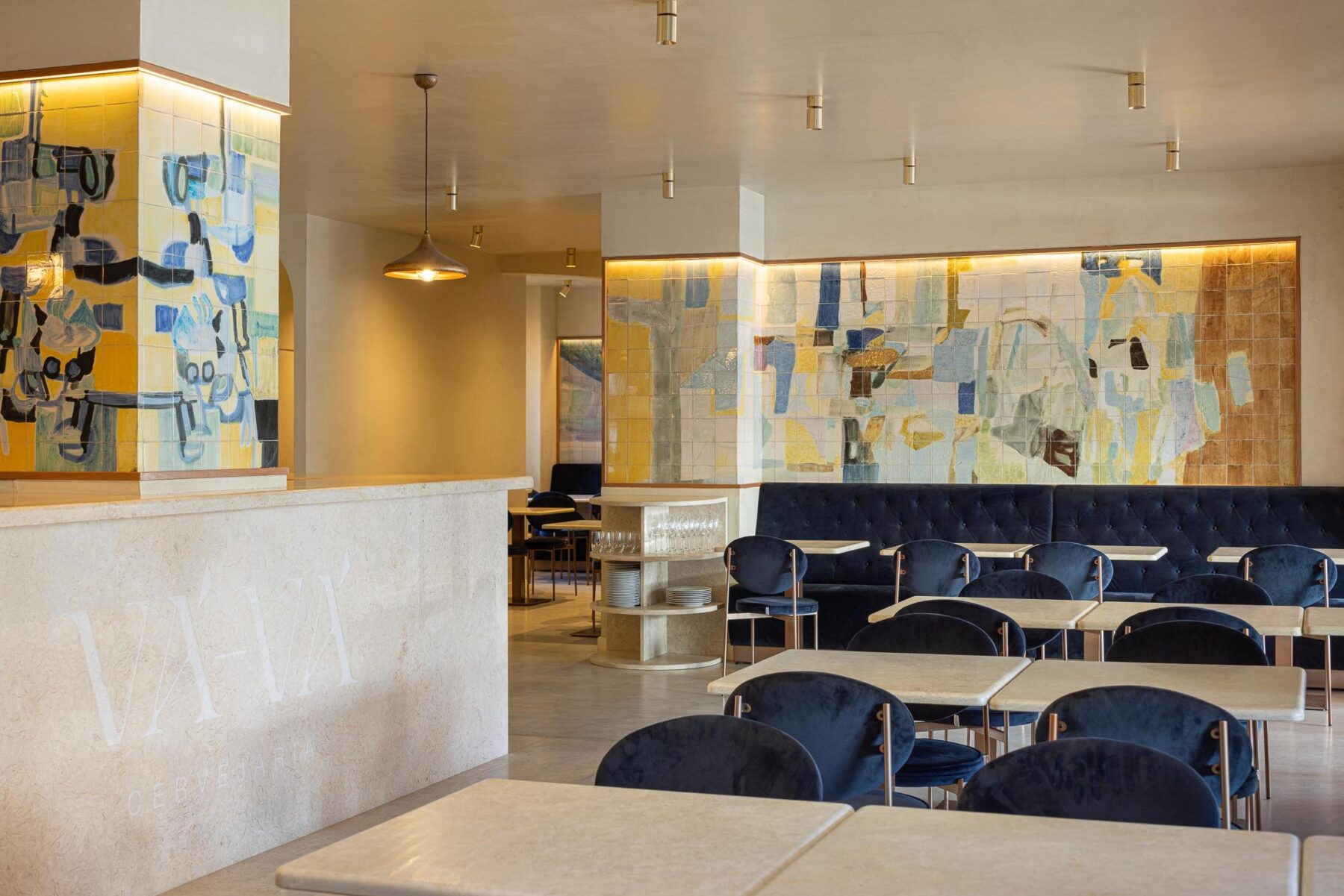 Salão: Vista geral do salão com balcão, painel de azulejos, mesas e cadeiras de veludo azul. — Cervejaria Vává - Requalificação arquitetura Rethorica Studio em Lisboa