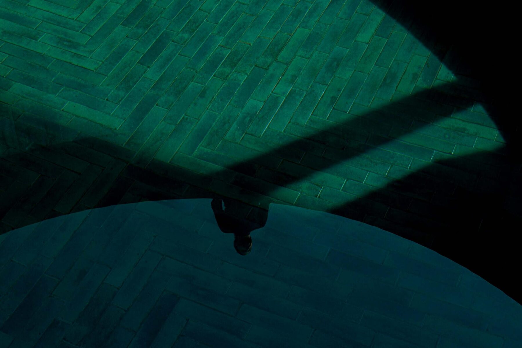 Reflexo de uma pessoa na água da piscina, com pavimento em tijoleira verde disposta em espinha. — Mimosa House arquitetura Pedro Henrique Arquitecto em Esmoriz