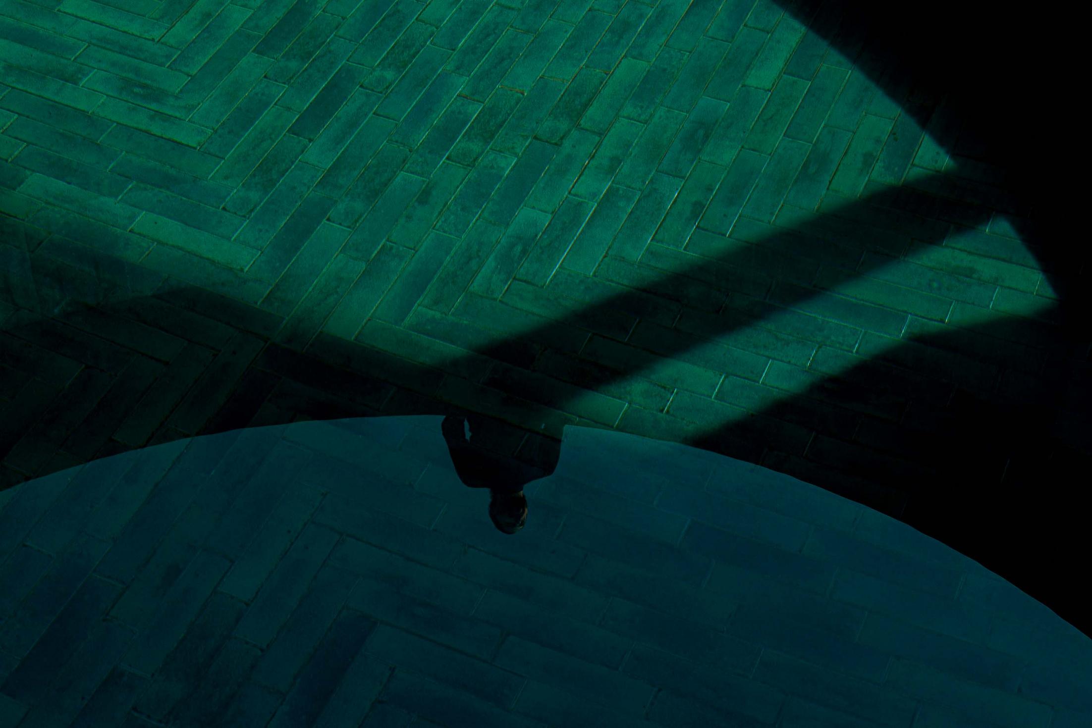 Reflexo de uma pessoa na água da piscina, com pavimento em tijoleira verde disposta em espinha. — Mimosa House arquitetura Pedro Henrique Arquitecto em Esmoriz