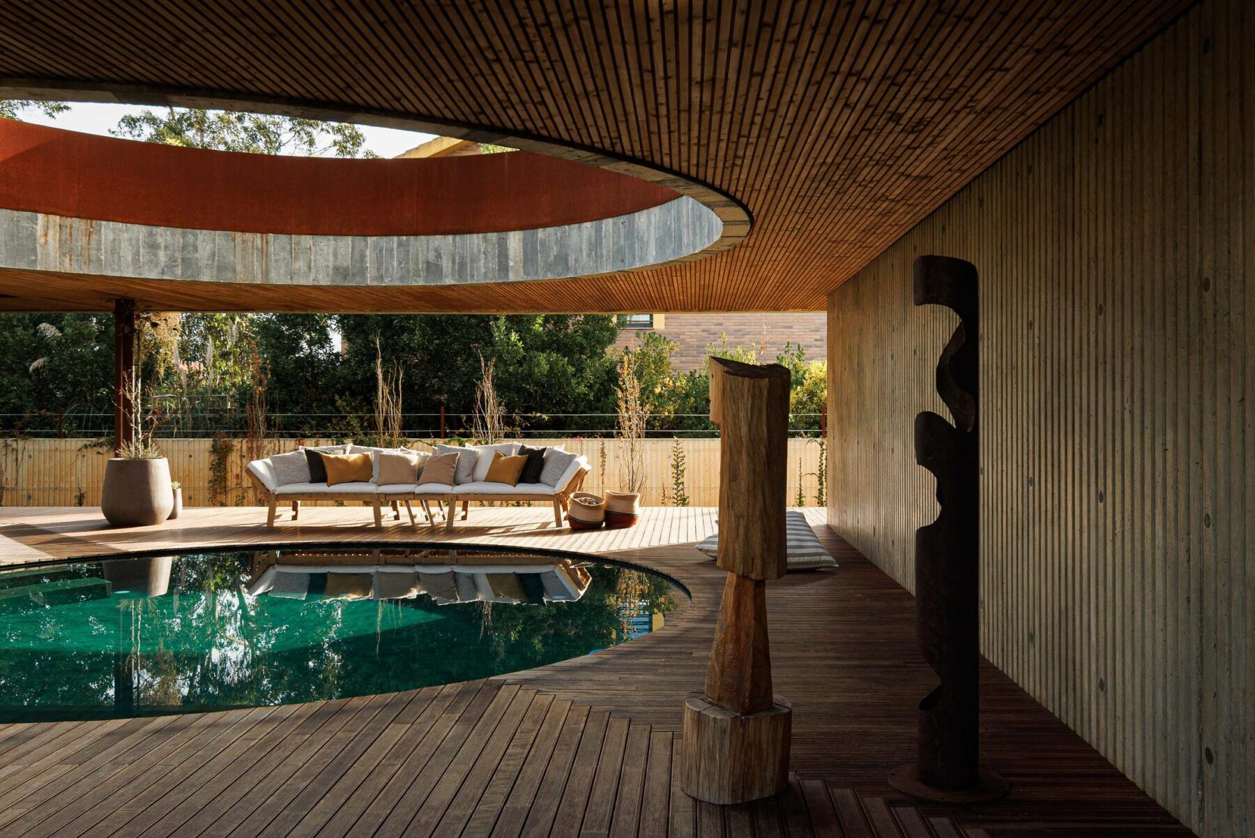 Detalhe da piscina com esculturas de madeira, deck e paredes em betão aparente com ripas. — Mimosa House arquitetura Pedro Henrique Arquitecto em Esmoriz