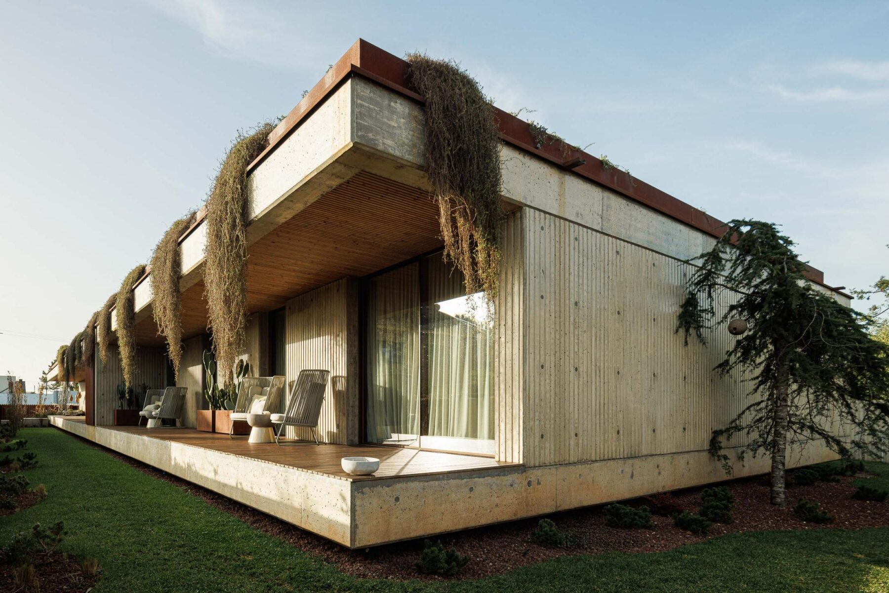 Fachada da casa com varanda, vegetação pendente e revestimento em betão aparente. — Mimosa House arquitetura Pedro Henrique Arquitecto em Esmoriz