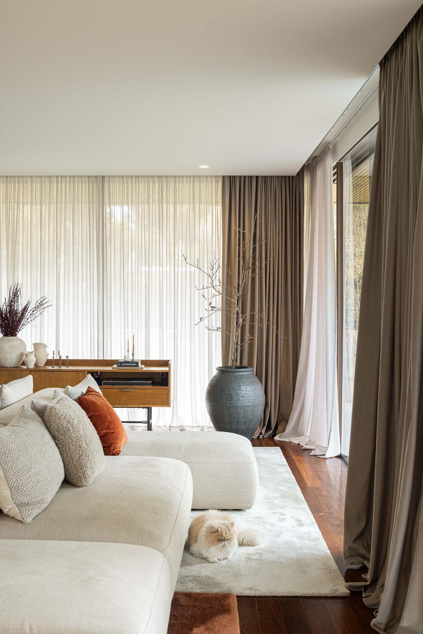 Sala de estar com sofá, alcatifa, cortinas e aparador de madeira com decoração. — Mimosa House arquitetura Pedro Henrique Arquitecto em Esmoriz