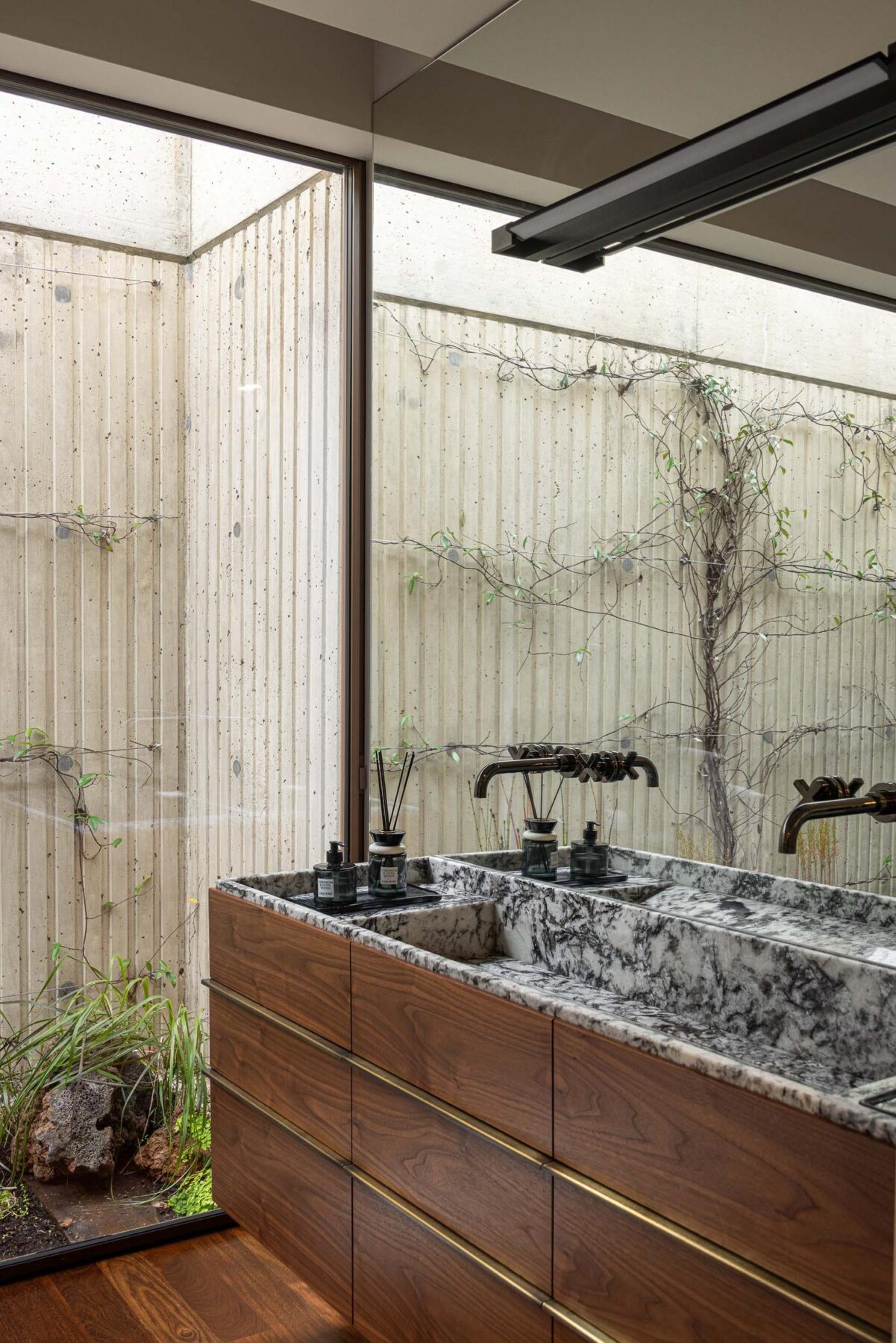 Lavatório duplo com bancada em mármore, espelho e vista para um pátio interior. — Mimosa House arquitetura Pedro Henrique Arquitecto em Esmoriz