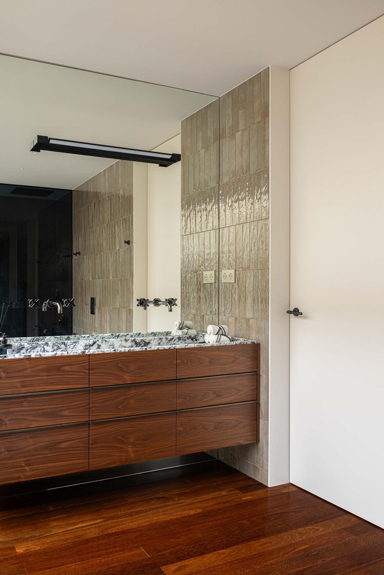 Lavatório com espelho, revestimento em azulejo bege e armários em madeira. — Mimosa House arquitetura Pedro Henrique Arquitecto em Esmoriz