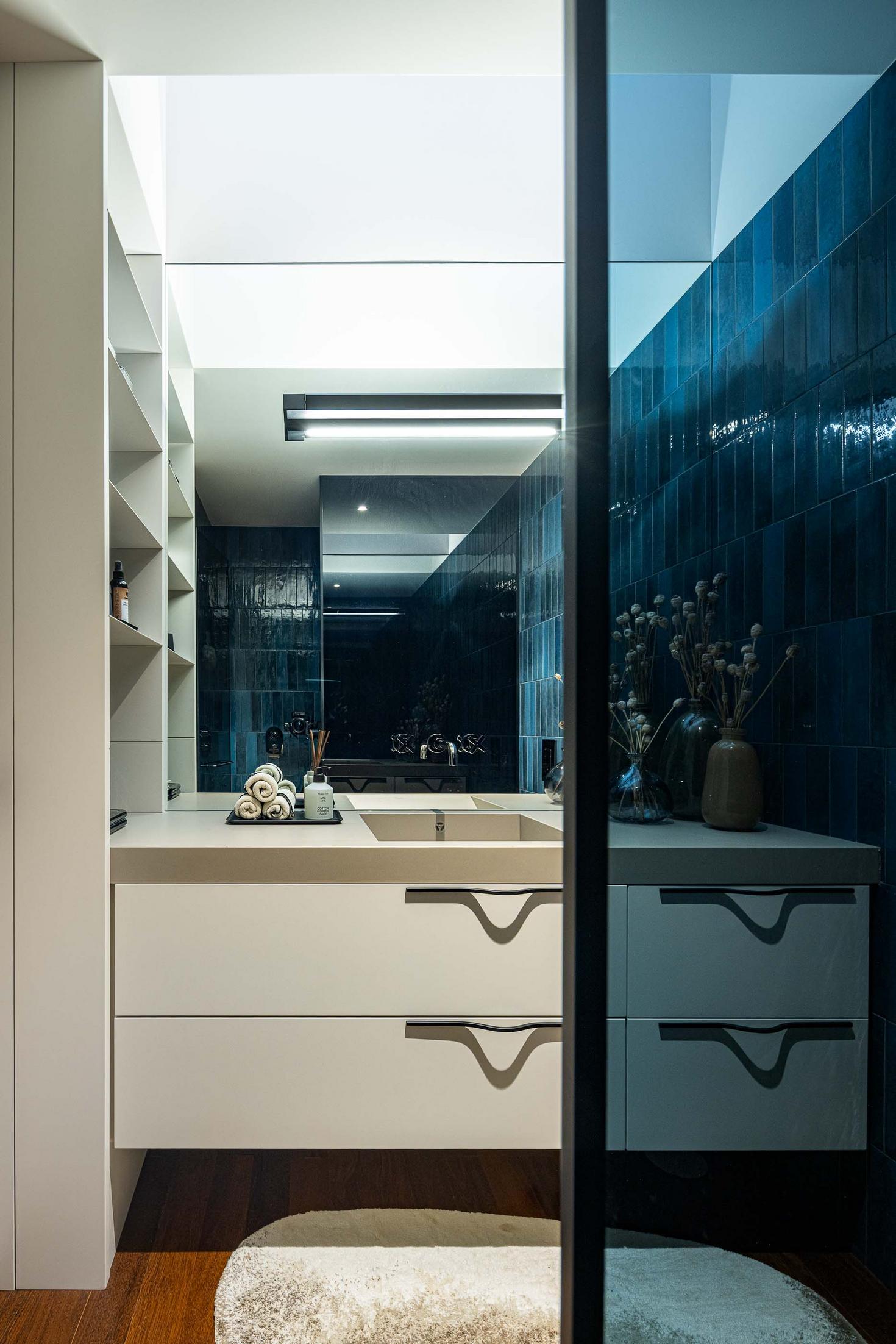 Casa de banho com lavatório branco, espelho e revestimento em azulejo azul. — Mimosa House arquitetura Pedro Henrique Arquitecto em Esmoriz