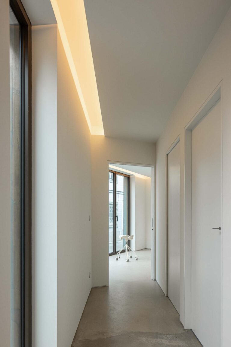 Corredor: Corredor minimalista branco com iluminação embutida e pavimento em cimento afagado. — Beira Mar II arquitetura Paulo Martins Arquitectura e Design em Aveiro