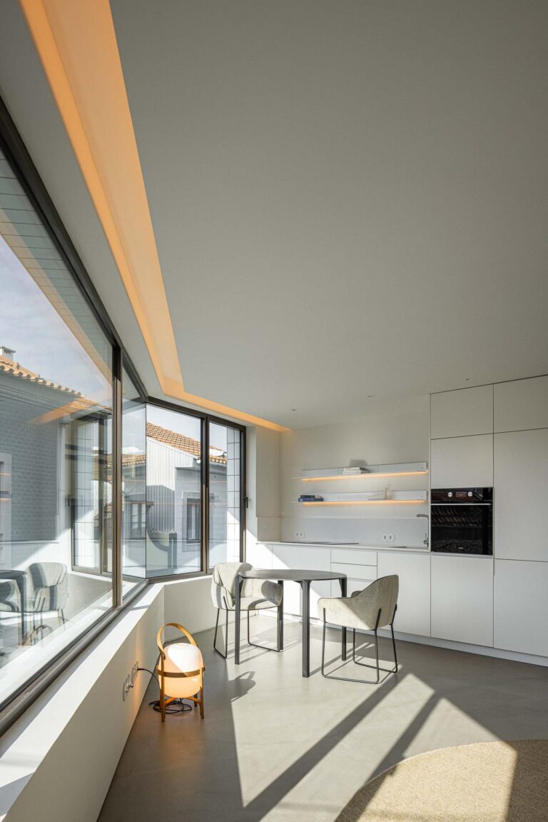 Cozinha: Cozinha moderna branca com mesa de jantar, cadeiras cinzentas e grande janela panorâmica. — Beira Mar II arquitetura Paulo Martins Arquitectura e Design em Aveiro