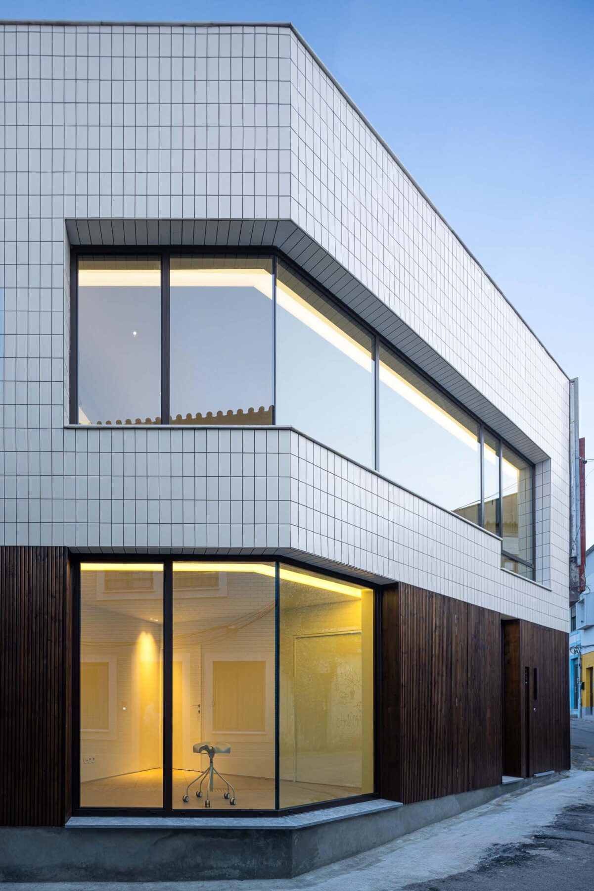 Fachada: Perspectiva da fachada com revestimento cerâmico branco e madeira escura, janelas amplas. — Beira Mar II arquitetura Paulo Martins Arquitectura e Design em Aveiro