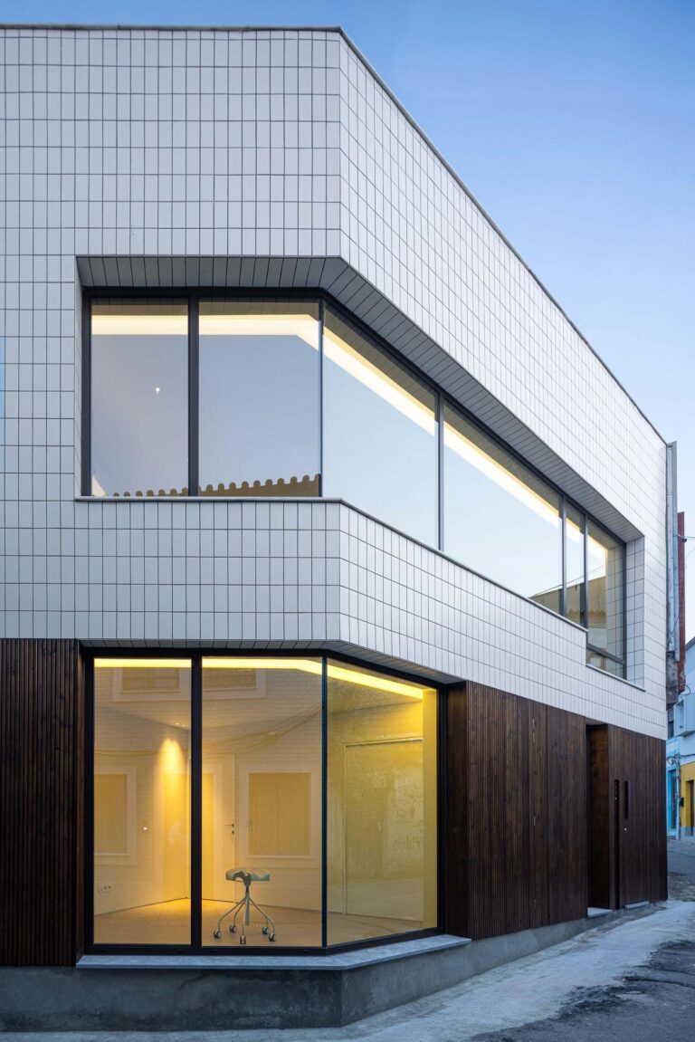 Fachada: Perspectiva da fachada com revestimento cerâmico branco e madeira escura, janelas amplas. — Beira Mar II arquitetura Paulo Martins Arquitectura e Design em Aveiro