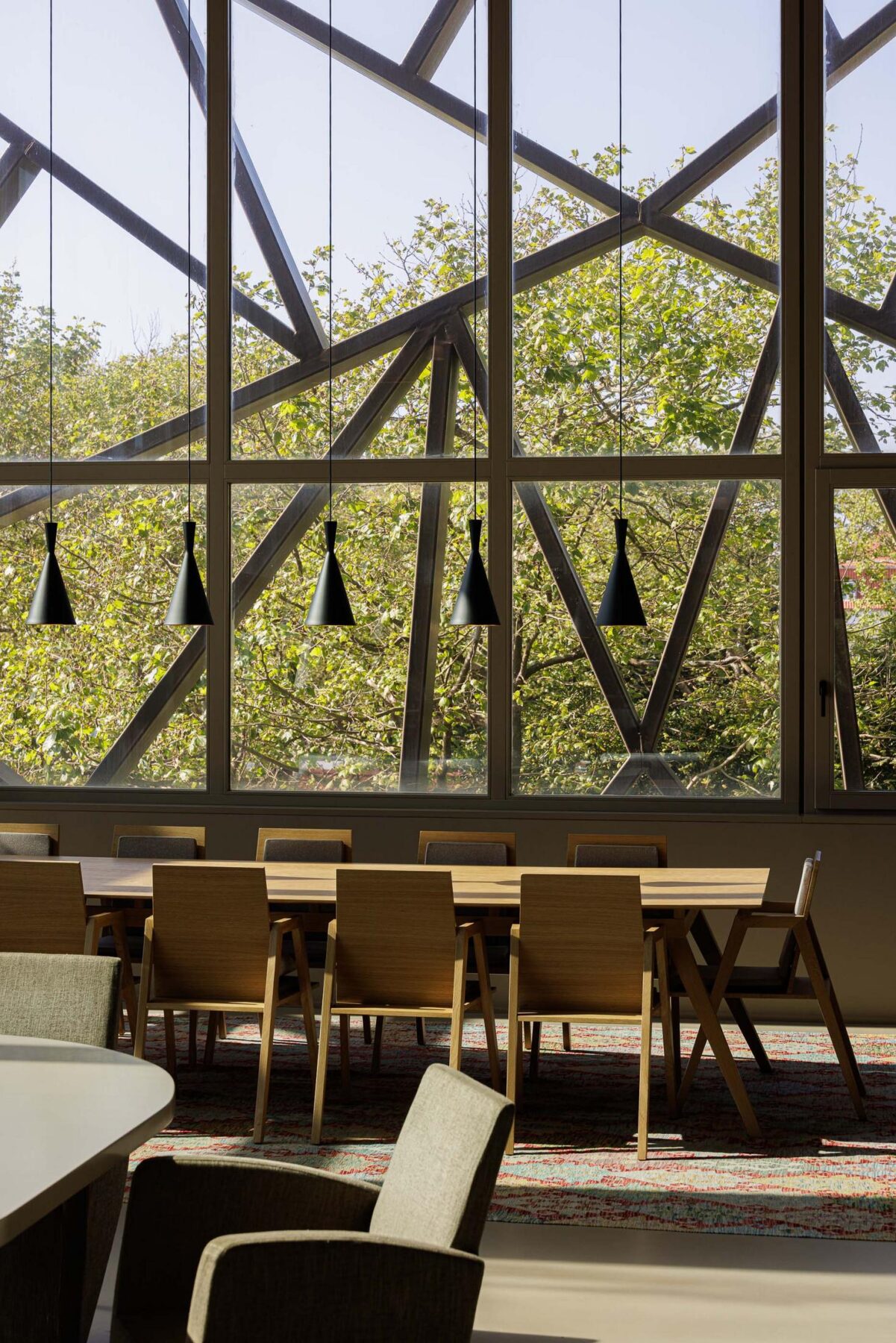 Sala de jantar: Sala de jantar com mesa comprida, cadeiras de madeira e estrutura metálica. — Assembleia da Granja arquitetura Lousinha Arquitectos em Vila Nova de Gaia