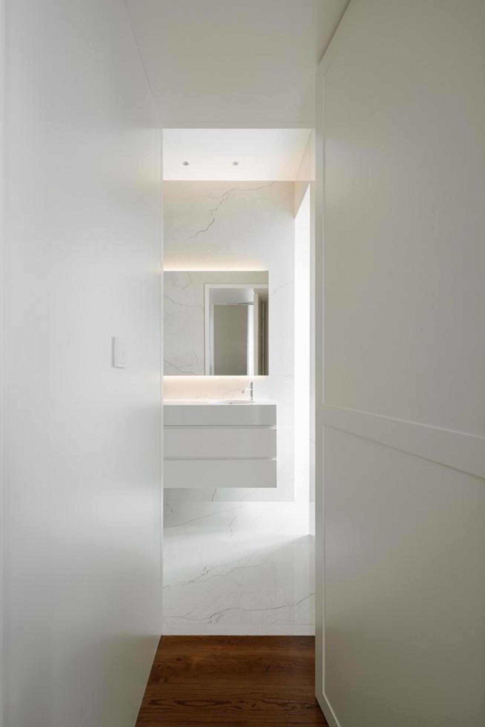 Vão de porta. Portas duplas brancas com painéis e caixilho superior envidraçado. Pavimento em madeira mel — Casa T+A Açores arquitectura Lopes da Costa fotografia Ivo Tavares