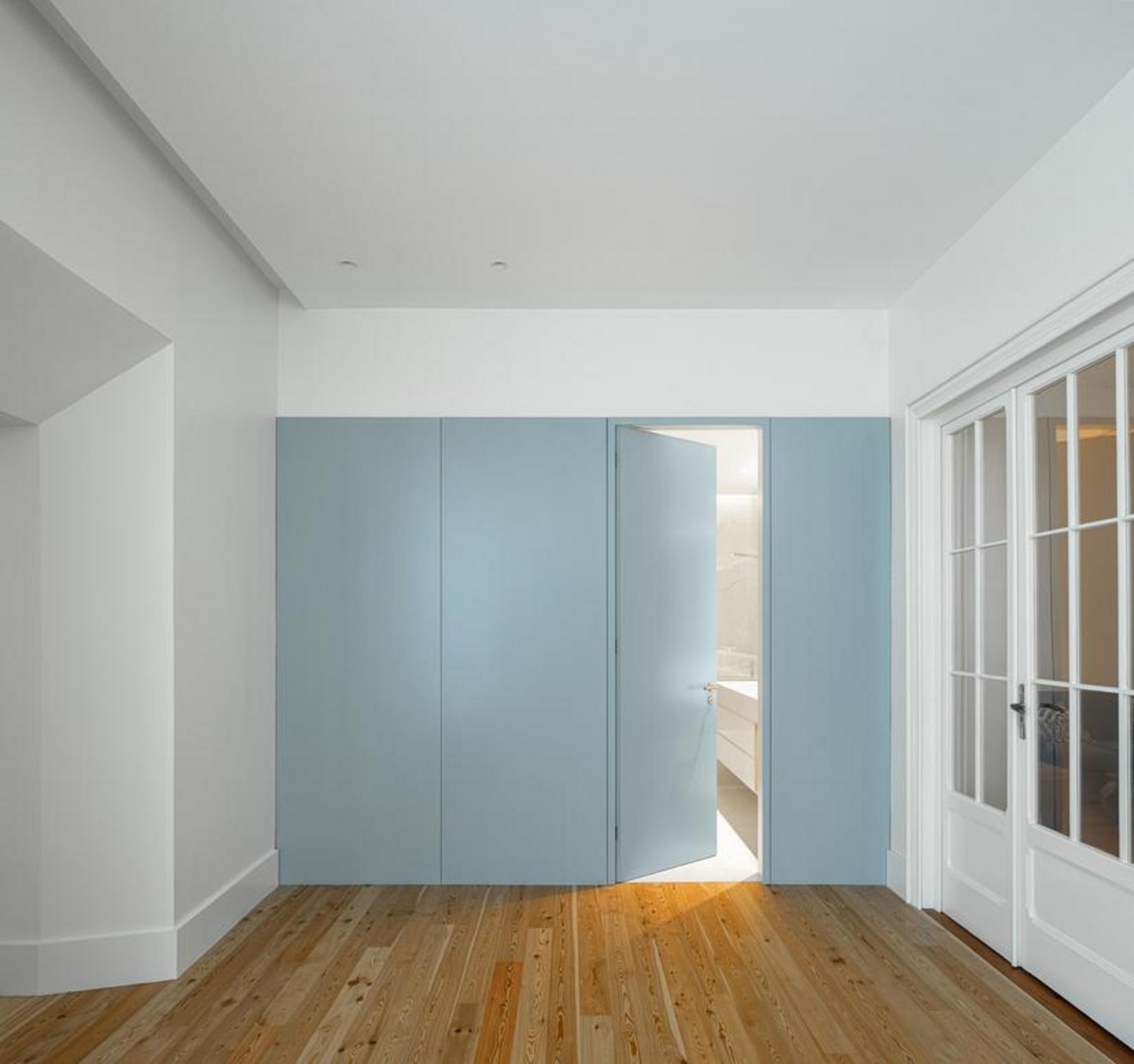 Cozinha. Teto abobadado branco, armários azuis claros e bancada branca. Pavimento em madeira clara e padrão geométrico preto e branco — Casa T+A Açores arquitectura Lopes da Costa fotografia Ivo Tavares