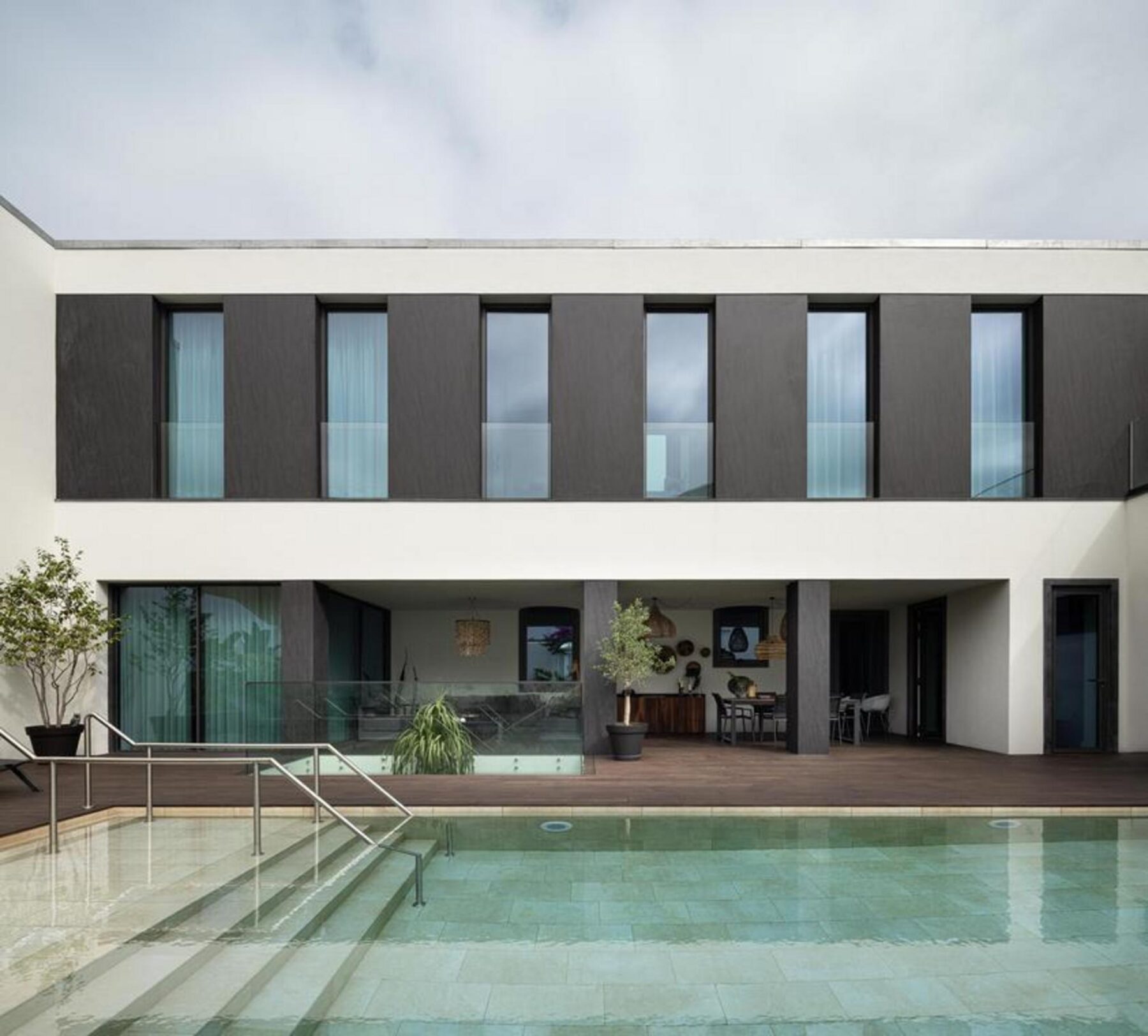Vista lateral da habitação e do jardim, onde a volumetria existente se integra no lote, com a piscina elevada como elemento central. — Casa T+A Açores . T+A . Azores House arquitectura Atelier d’arquitectura Lopes da Costa fotografia Ivo Tavares