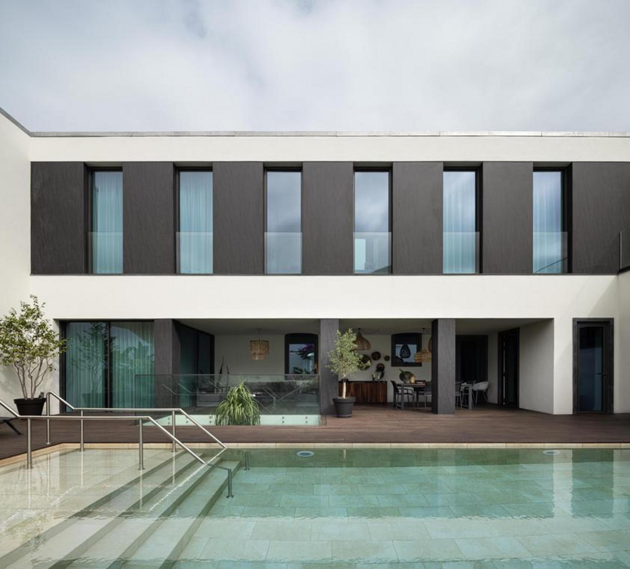 Casa de banho. Pavimento em madeira mel e mármore branco. Móvel branco suspenso com nicho iluminado. Sanita ao fundo — Casa T+A Açores arquitectura Lopes da Costa fotografia Ivo Tavares