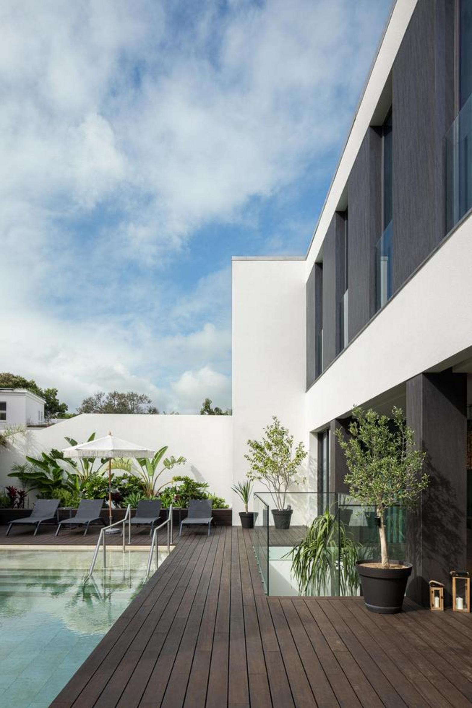 Quarto. Pavimento em madeira clara, paredes brancas e painel azul claro. Cama cinzenta, cómoda escura e mesas de cabeceira pretas — Casa T+A Açores arquitectura Lopes da Costa fotografia Ivo Tavares