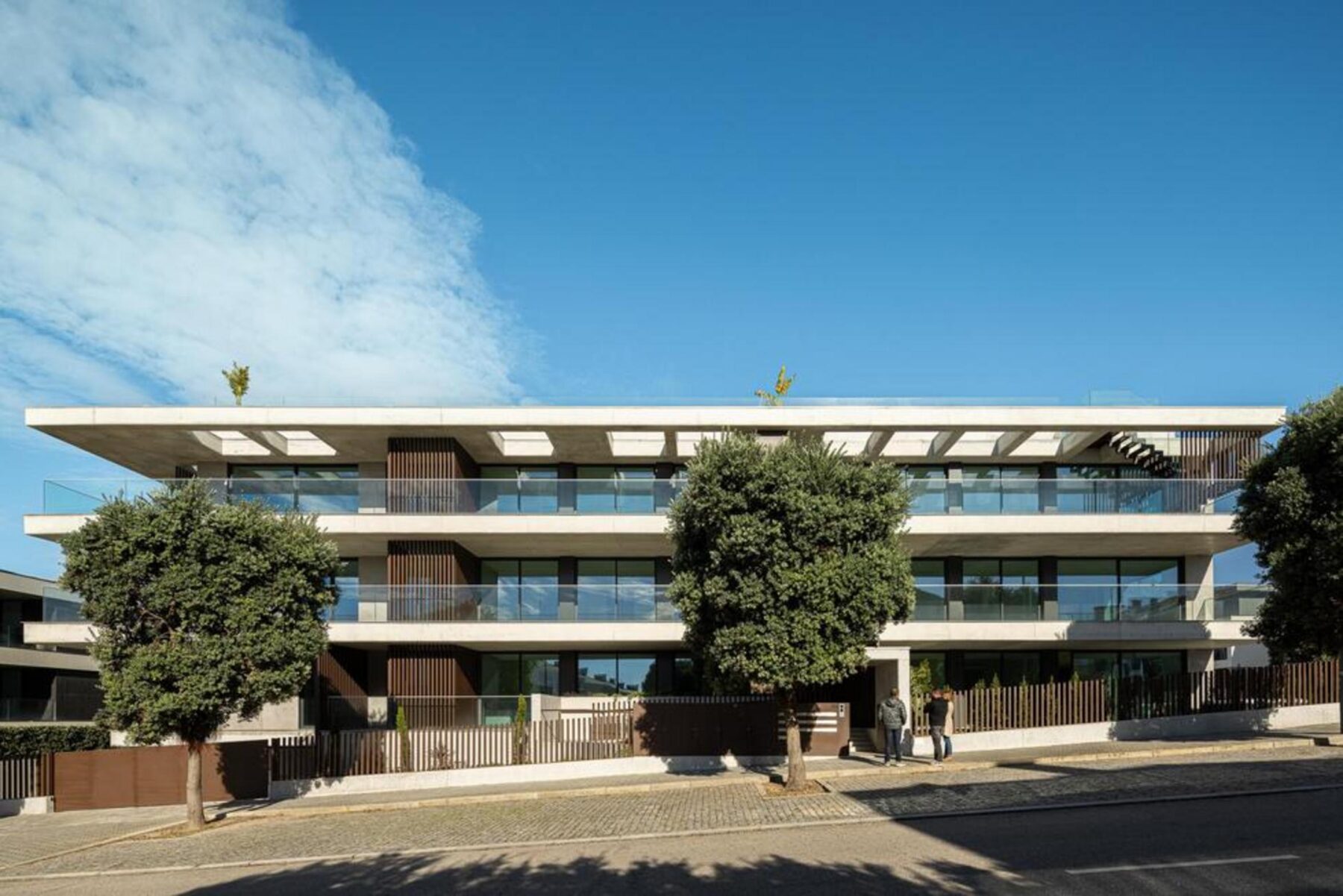 Cozinha com ilha: Ilha central em pedra escura, com placa de indução e exaustor integrado, ideal para refeições informais. — Edifício Scala-Mare arquitectura Atelier d’Arquitectura Lopes da Costa fotografia Ivo Tavares