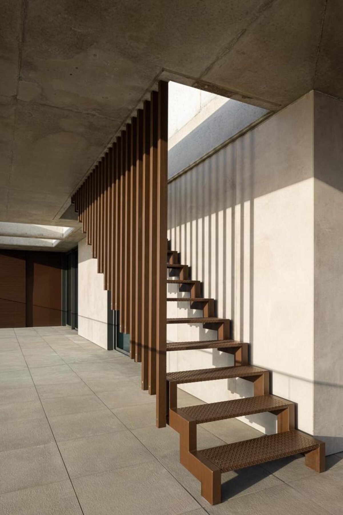 Escadaria comum: Degraus em betão polido e guarda-corpos metálicos, com iluminação natural através de um vão vertical, ligando os pisos. — Edifício Scala-Mare arquitectura Atelier d’Arquitectura Lopes da Costa fotografia Ivo Tavares