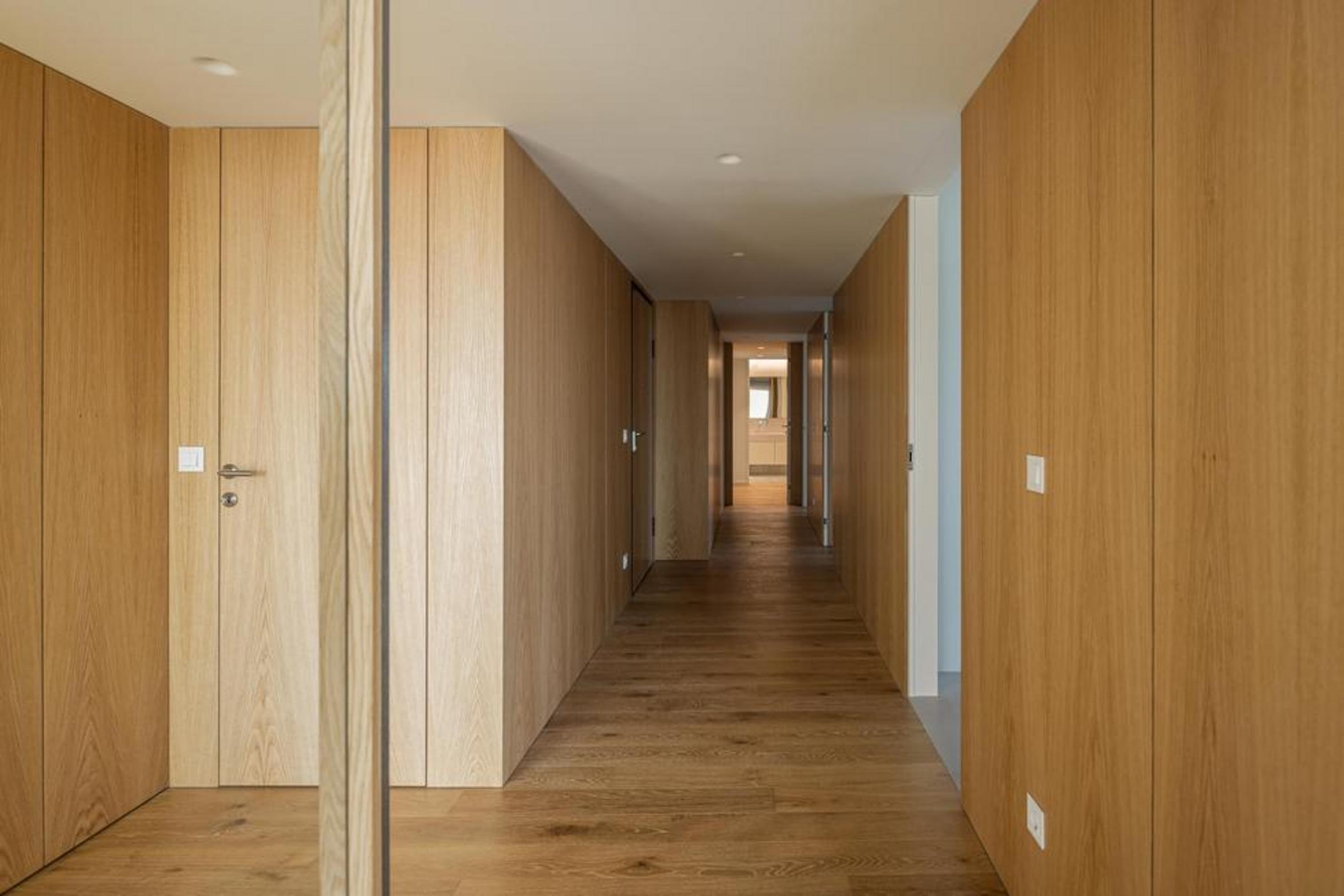 Corredor interior longo com pavimento em madeira de carvalho e paredes revestidas a painéis de madeira, com espelho — Edifício Scala-Mare arquitectura Lopes da Costa fotografia Ivo Tavares