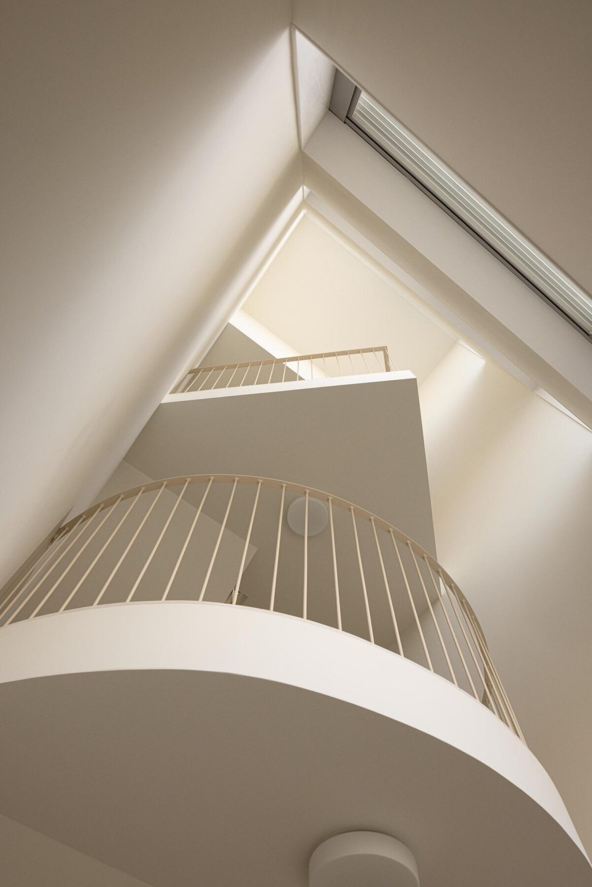 Escada em betão branco com guardas metálicas, iluminada zenitalmente, destacando a geometria e a leveza da estrutura. — EDIFÍCIO DE HABITAÇÃO MULTIFAMILIAR HINTZE RIBEIRO arquitectura HELDER DA ROCHA ARQUITECTOS fotografia Ivo Tavares