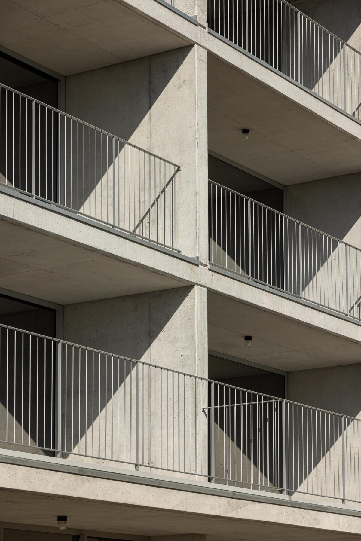 Detalhe das varandas em betão aparente com guardas metálicas, evidenciando a modulação e a repetição na fachada do edifício. — EDIFÍCIO DE HABITAÇÃO MULTIFAMILIAR HINTZE RIBEIRO arquitectura HELDER DA ROCHA ARQUITECTOS fotografia Ivo Tavares