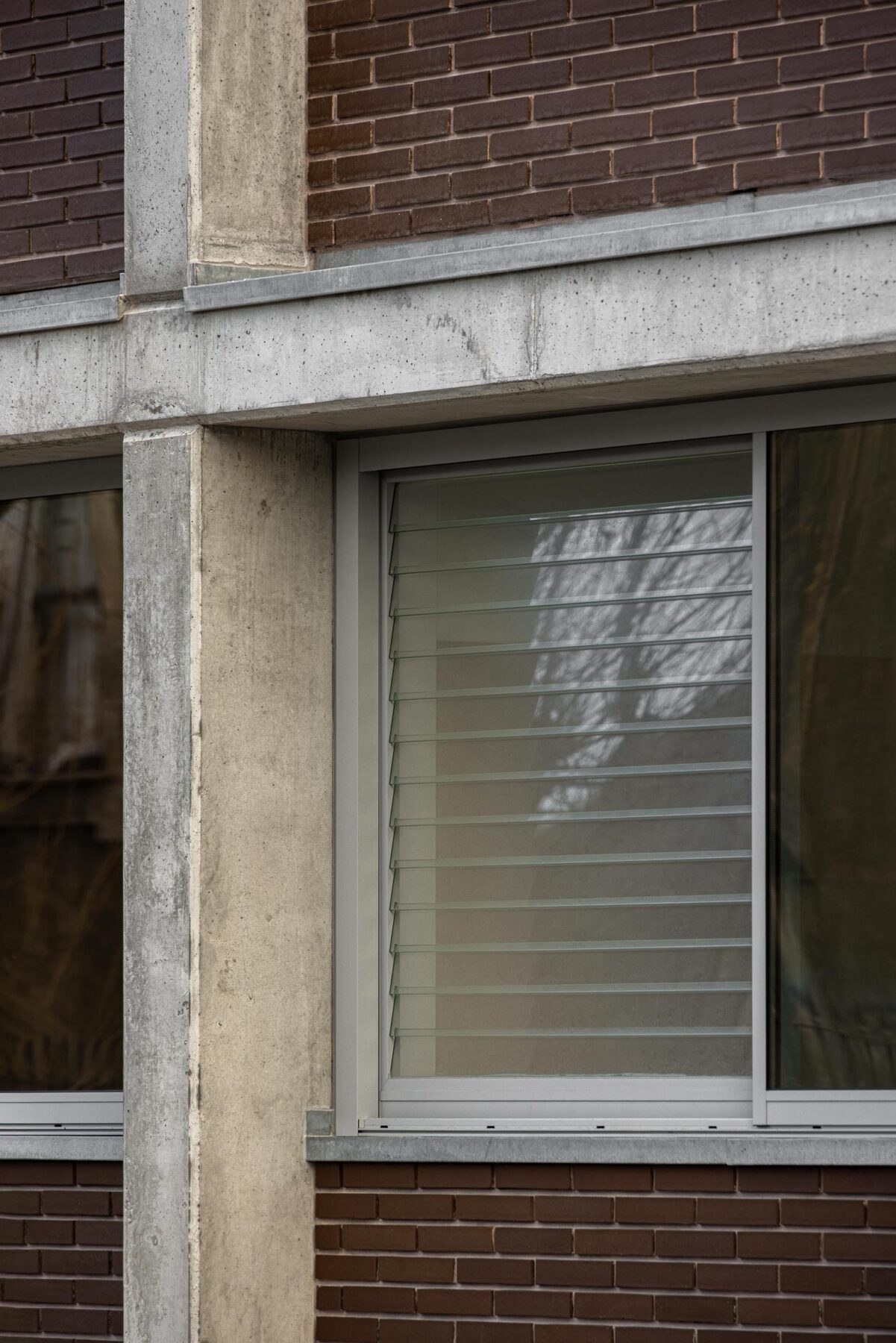 Detalhe da fachada com estrutura em betão aparente e preenchimento em tijolo maciço castanho, com venezianas nos vãos envidraçados. — EDIFÍCIO DE HABITAÇÃO MULTIFAMILIAR HINTZE RIBEIRO arquitectura HELDER DA ROCHA ARQUITECTOS fotografia Ivo Tavares
