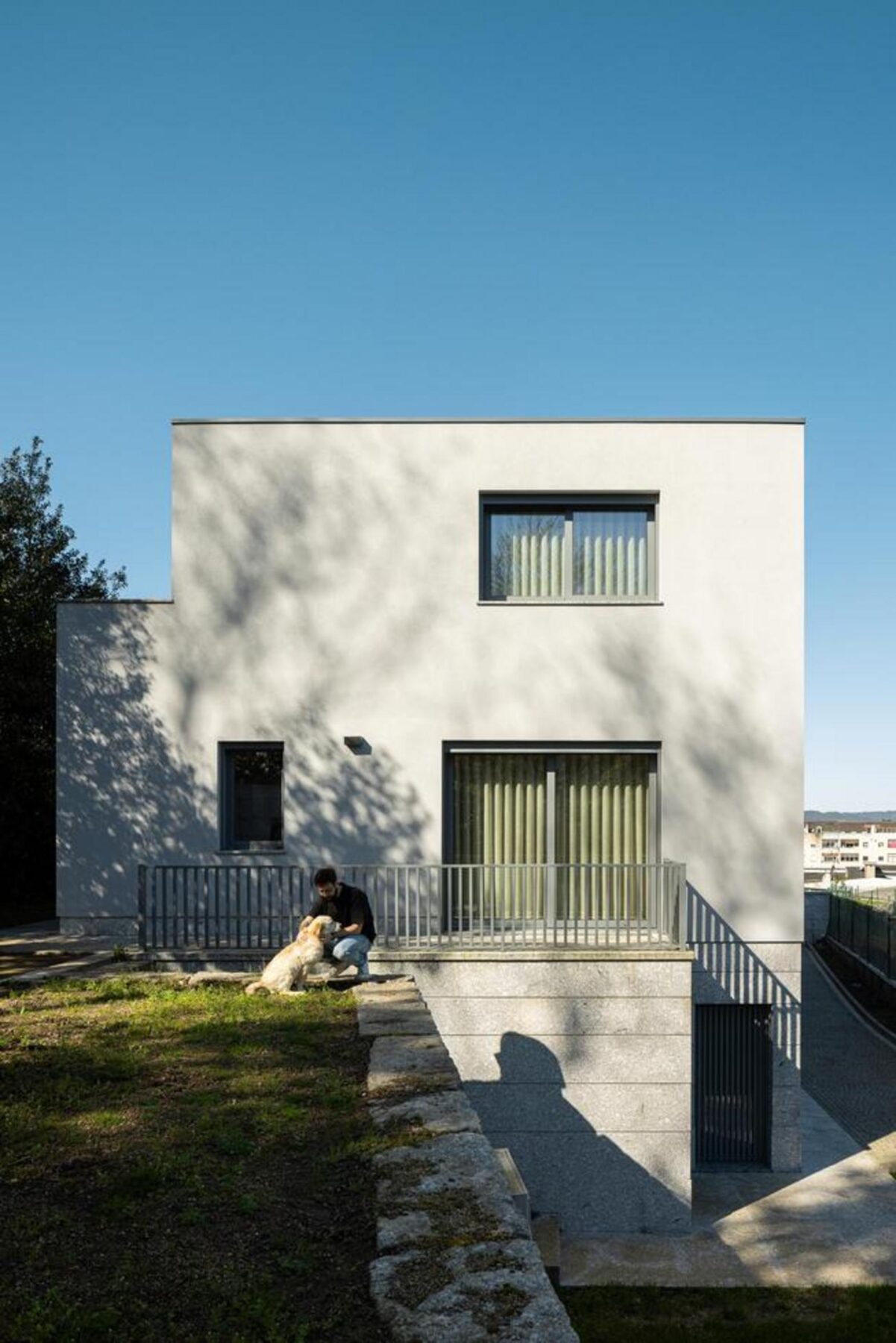 Perspetiva interior que mostra a fluidez entre a sala de estar e um pátio exterior, através de um grande vão de correr. — Duas casas em Guimarães arquitectura felixARQS – Daniel Félix Arquitectos fotografia Ivo Tavares