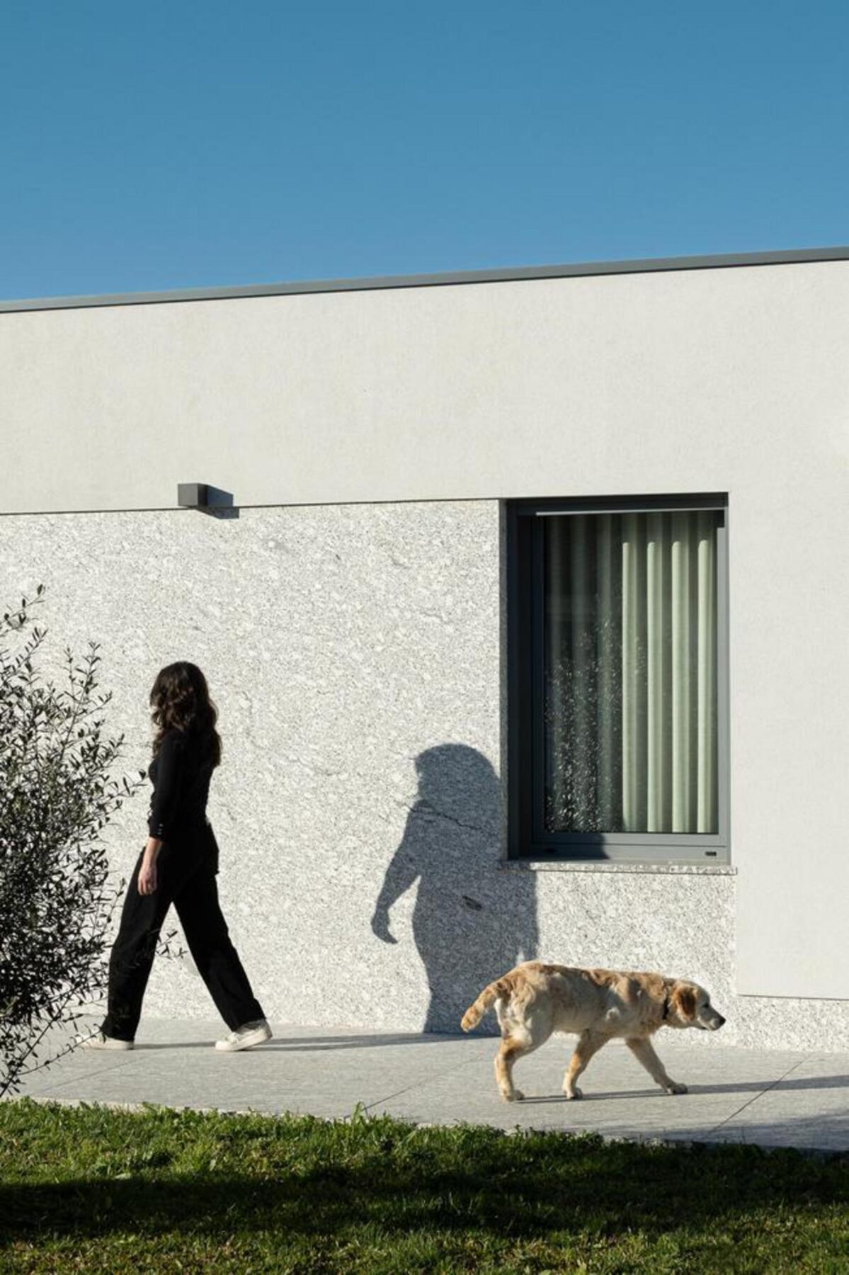 Terraço exterior coberto, com pavimento em pedra e teto em madeira, oferecendo um espaço protegido para a vida familiar. — Duas casas em Guimarães arquitectura felixARQS – Daniel Félix Arquitectos fotografia Ivo Tavares