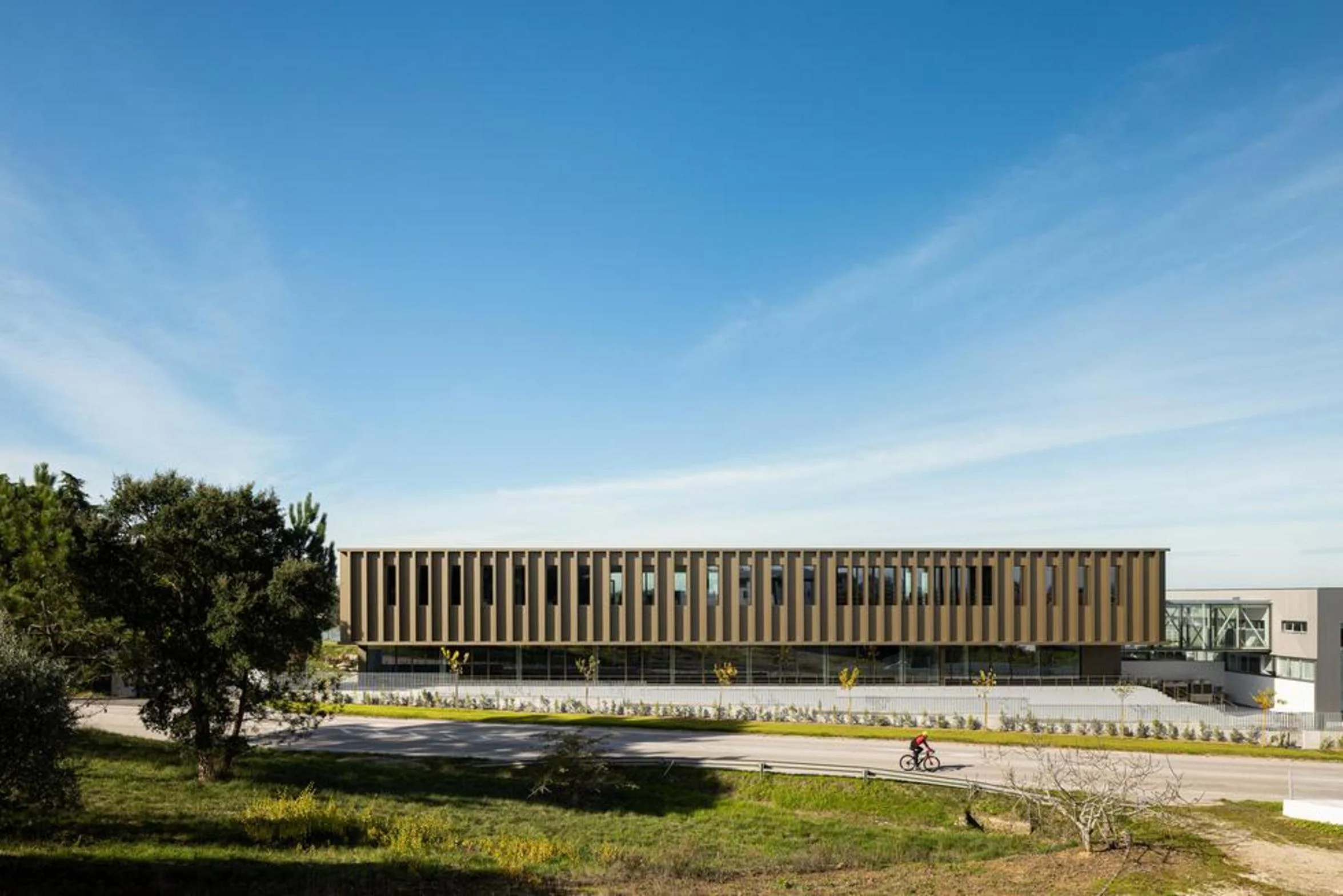 Perspetiva lateral do complexo industrial e administrativo, onde o bet&atilde;o aparente e o vidro estrutural definem a linguagem arquitect&oacute;nica contempor&acirc;nea. &mdash; EDIF&Iacute;CIO-SEDE PRF arquitectura Impare Arquitectura fotografia Ivo Tavares