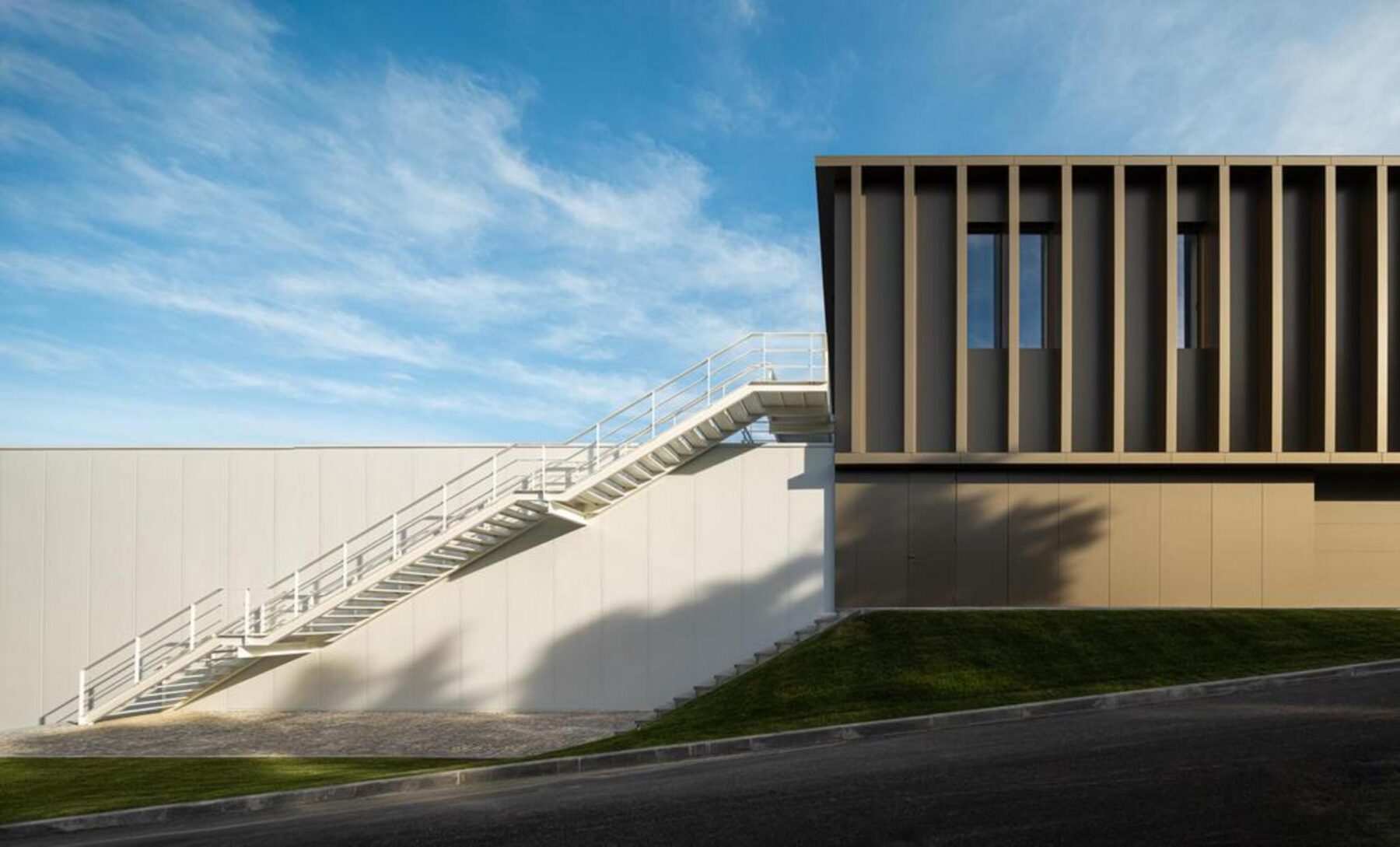 Fachada principal do edifício-sede, com volume compacto em betão aparente cinzento e grandes vãos envidraçados, consolidando a frente edificada. — EDIFÍCIO-SEDE PRF arquitectura Impare Arquitectura fotografia Ivo Tavares