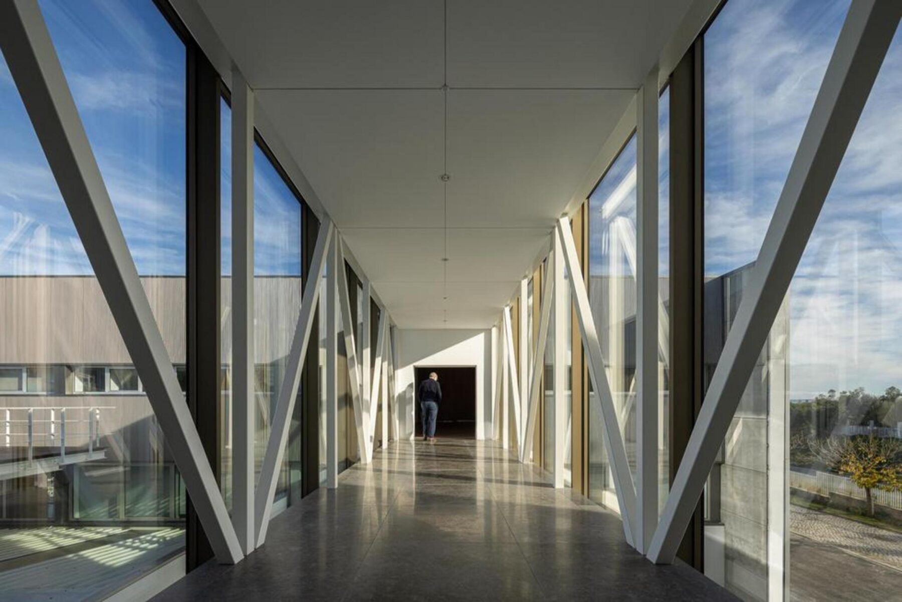 Detalhe da materialidade da fachada, onde a textura do betão aparente se harmoniza com os caixilhos metálicos escuros dos vãos. — EDIFÍCIO-SEDE PRF arquitectura Impare Arquitectura fotografia Ivo Tavares