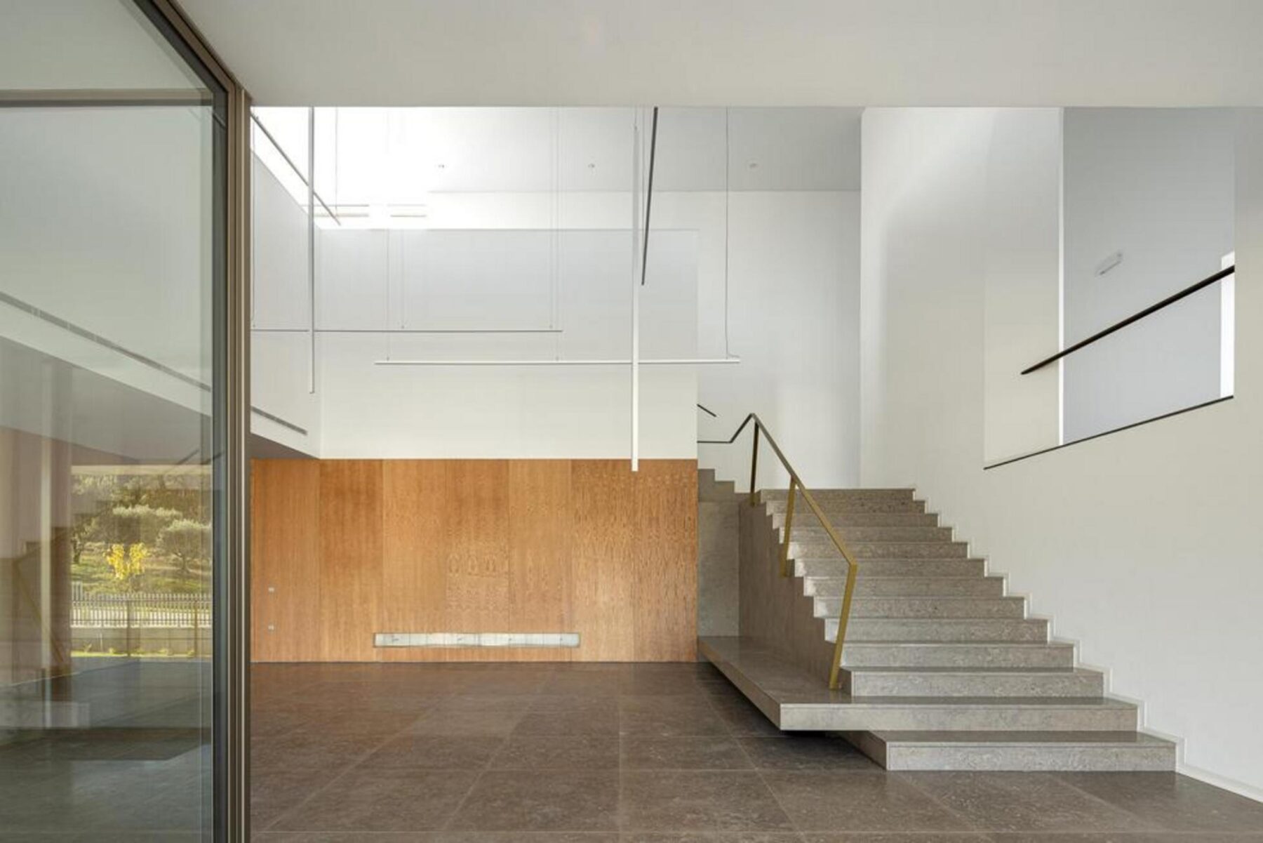 Interior do hall de entrada com pé-direito duplo, revelando a escadaria em betão e a fluidez espacial que liga os diferentes níveis. — EDIFÍCIO-SEDE PRF arquitectura Impare Arquitectura fotografia Ivo Tavares